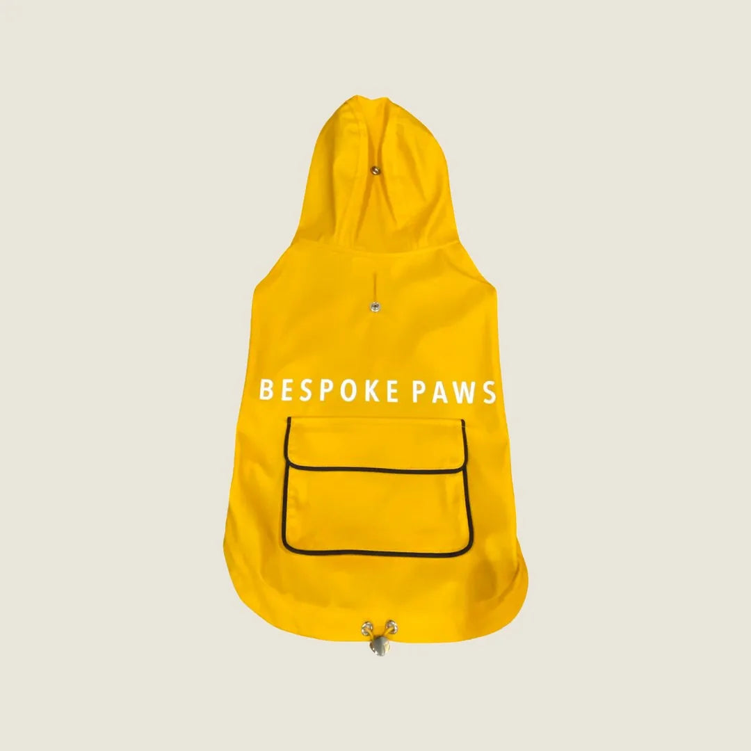 Bright yellow water-repellent pet raincoat with adjustable hoodie and pocket, featuring "BESPOKE PAWS" text on the back.