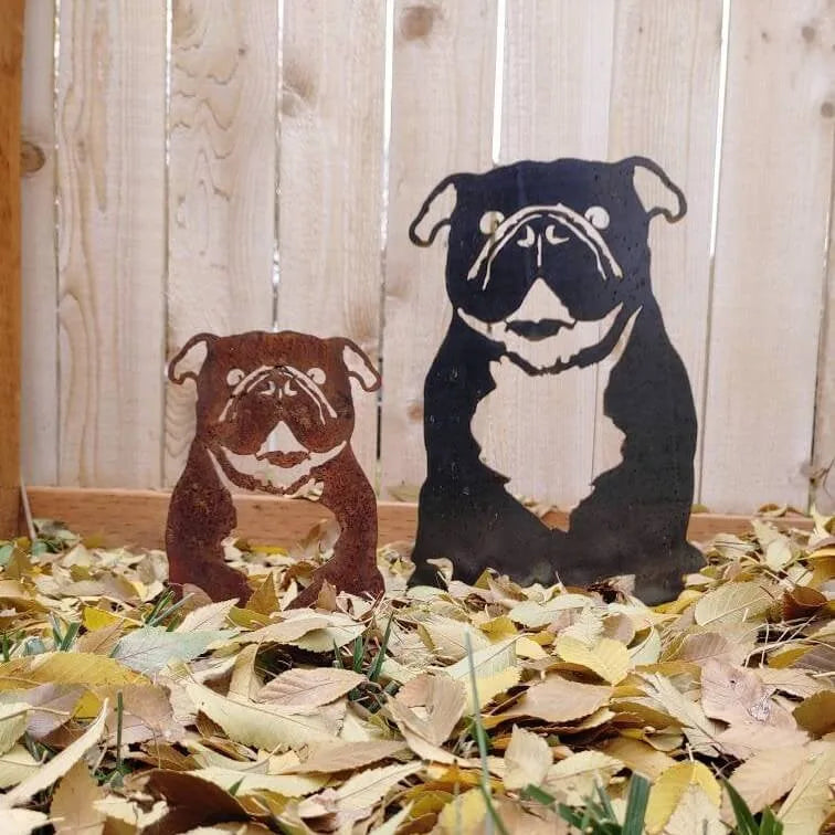 English Bulldog metal silhouettes in Corten steel and black, surrounded by autumn leaves on the ground.