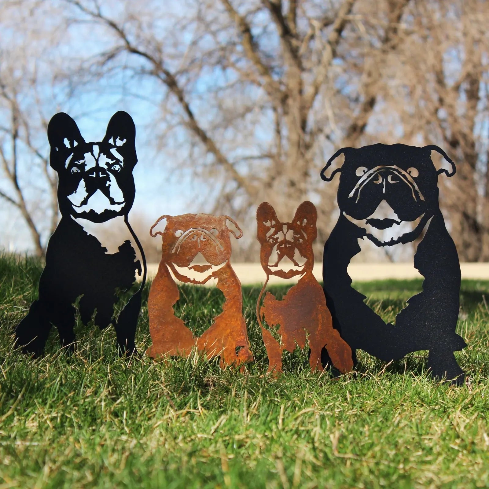 Metal silhouettes of English Bulldogs in black and rusted Corten steel, showcased in a grassy outdoor setting.
