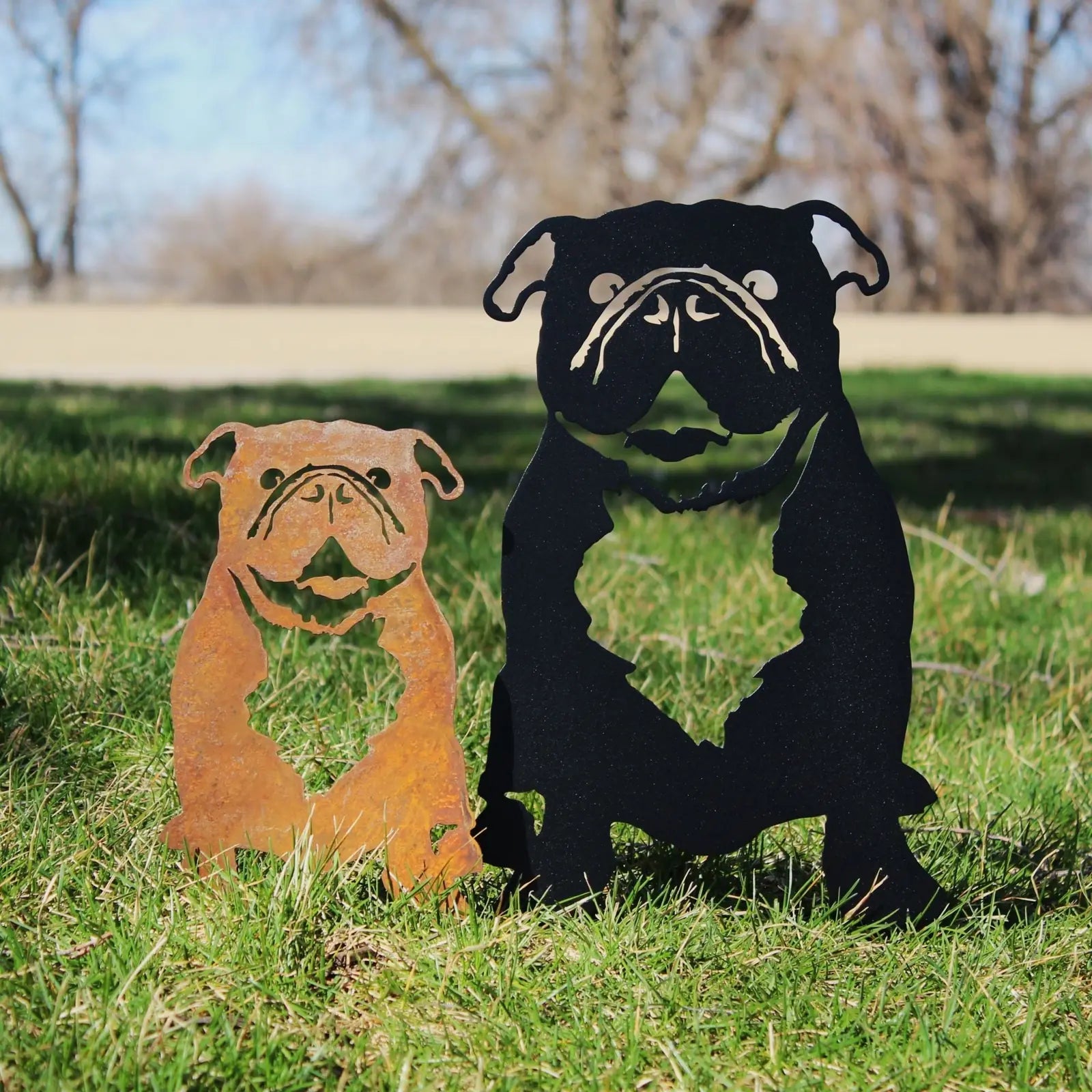 Two English Bulldog metal silhouettes in Corten steel and black powder-coated finish displayed on grass.