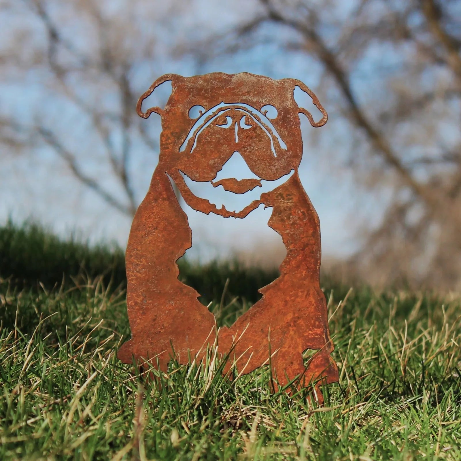 Rusty Corten steel silhouette of an English Bulldog, set against a green lawn and blue sky, showcasing dog decor artistry.