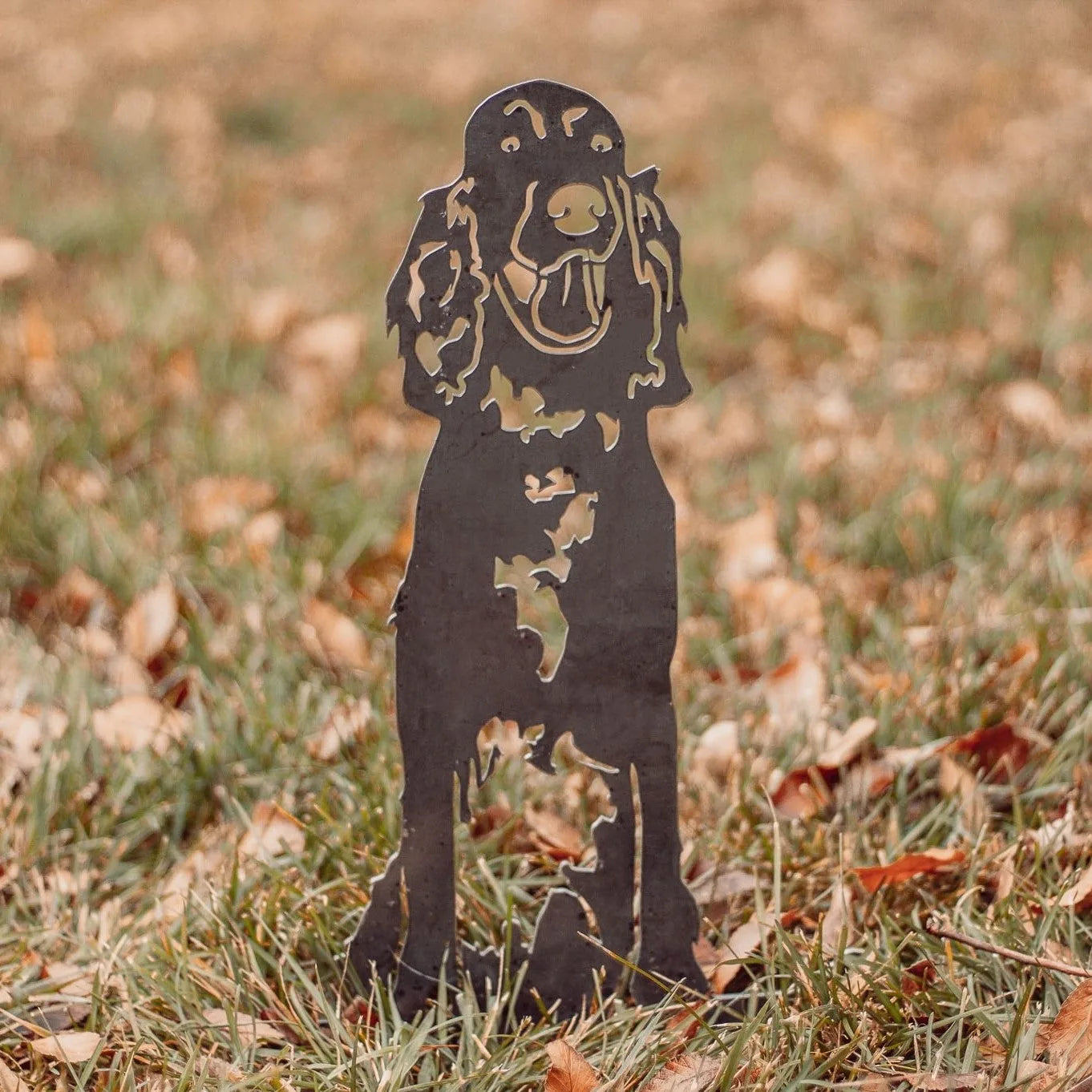 English Setter metal silhouette standing on grass among fallen leaves, crafted from weathering steel, showcasing a playful...