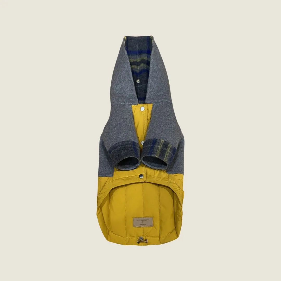 Reversible dog coat featuring navy plaid and yellow down-puffer design with a cozy hoodie and metal button closures.