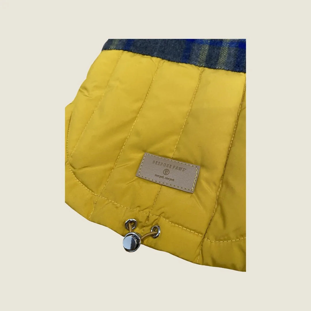 Reversible dog puffer hoodie in navy plaid and bright yellow, featuring a branded tag and adjustable metal stoppers.