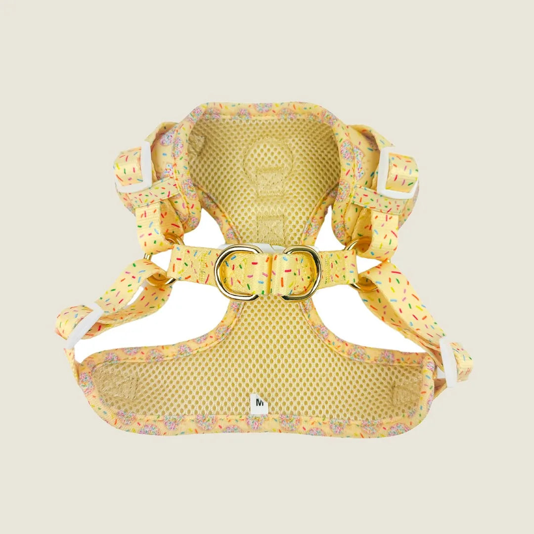 Yellow step-in dog harness with playful cookie and sprinkle print, made of soft neoprene with breathable mesh lining.