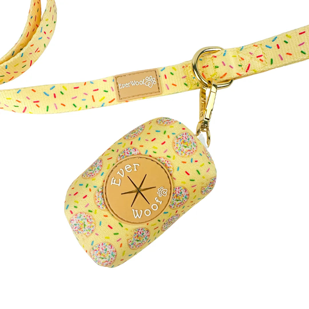 Yellow waste bag holder with donut pattern, featuring a gold EverWoof logo and a swivel hook for attachment.