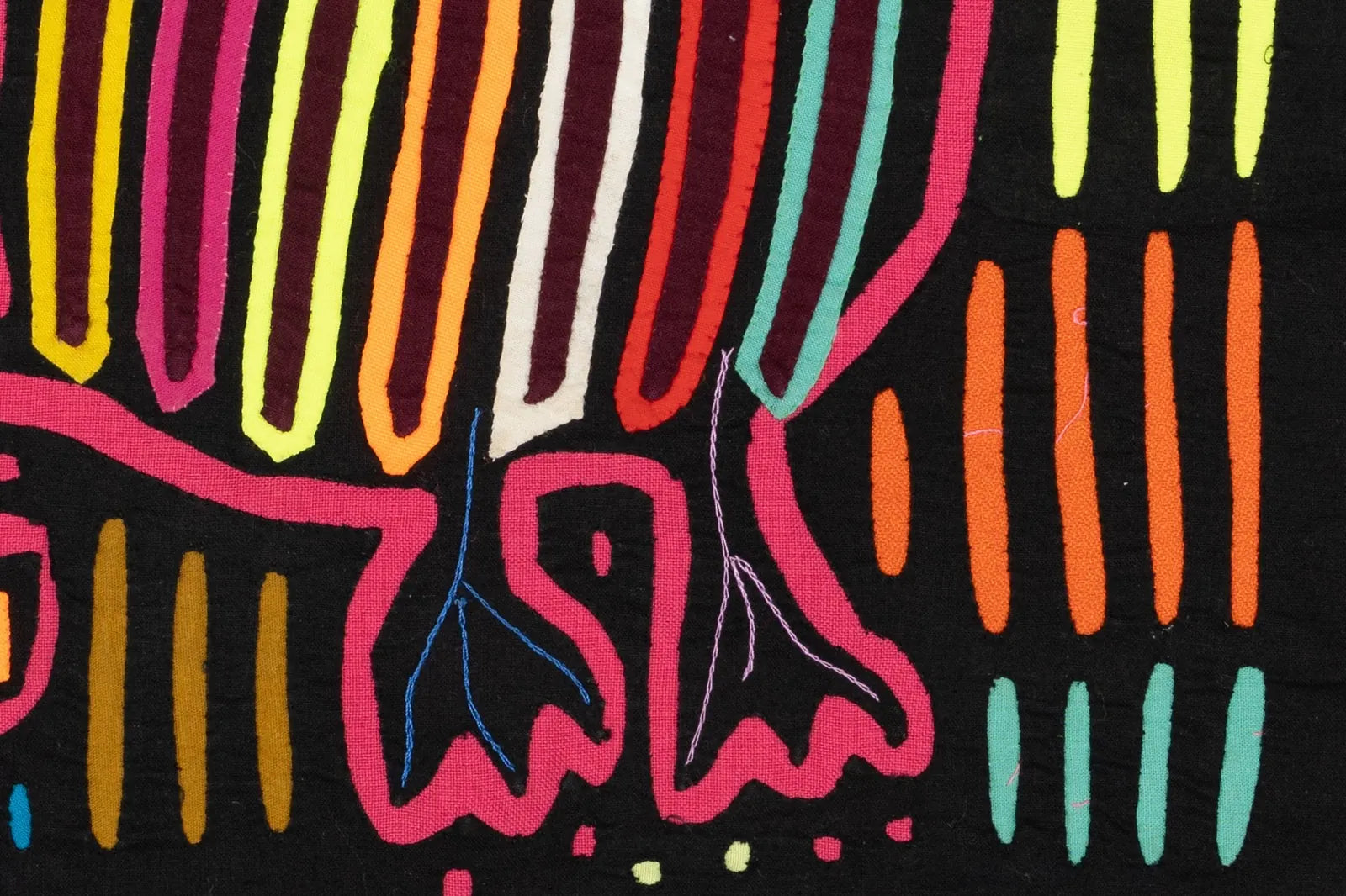 Vibrant hand-stitched Mola featuring geometric patterns in pink, orange, and green on a black background.