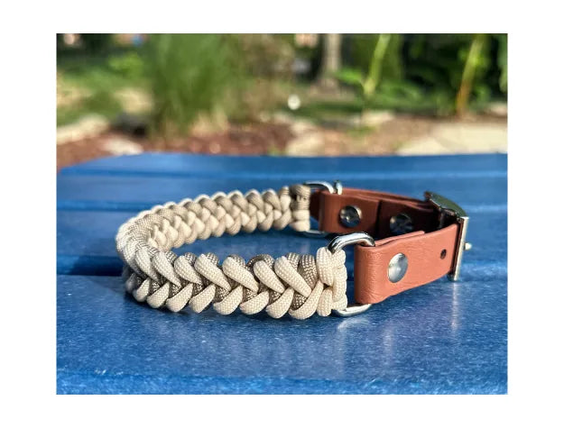 Tan and cream fishtail hand braided dog collar with a brown strap and silver hardware, set against a blue table.