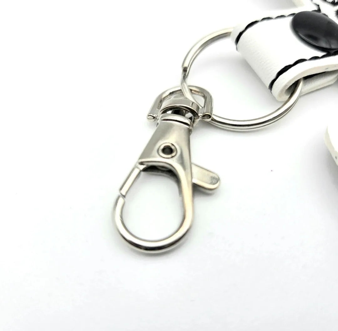 Silver swivel clip and split ring attached to a white keychain tab with contrasting black stitching.