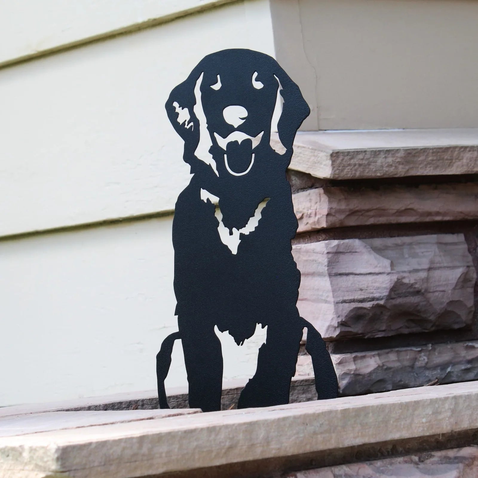 Handcrafted black metal silhouette of a Flat-Coated Retriever resting on stone steps, perfect for garden decor.