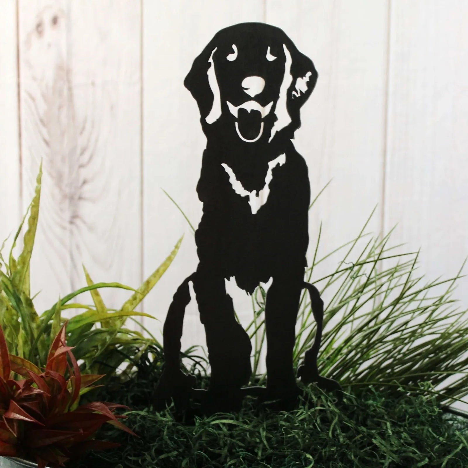 Handcrafted black metal silhouette of a Flat-Coated Retriever, displayed among green foliage, perfect for garden decor.