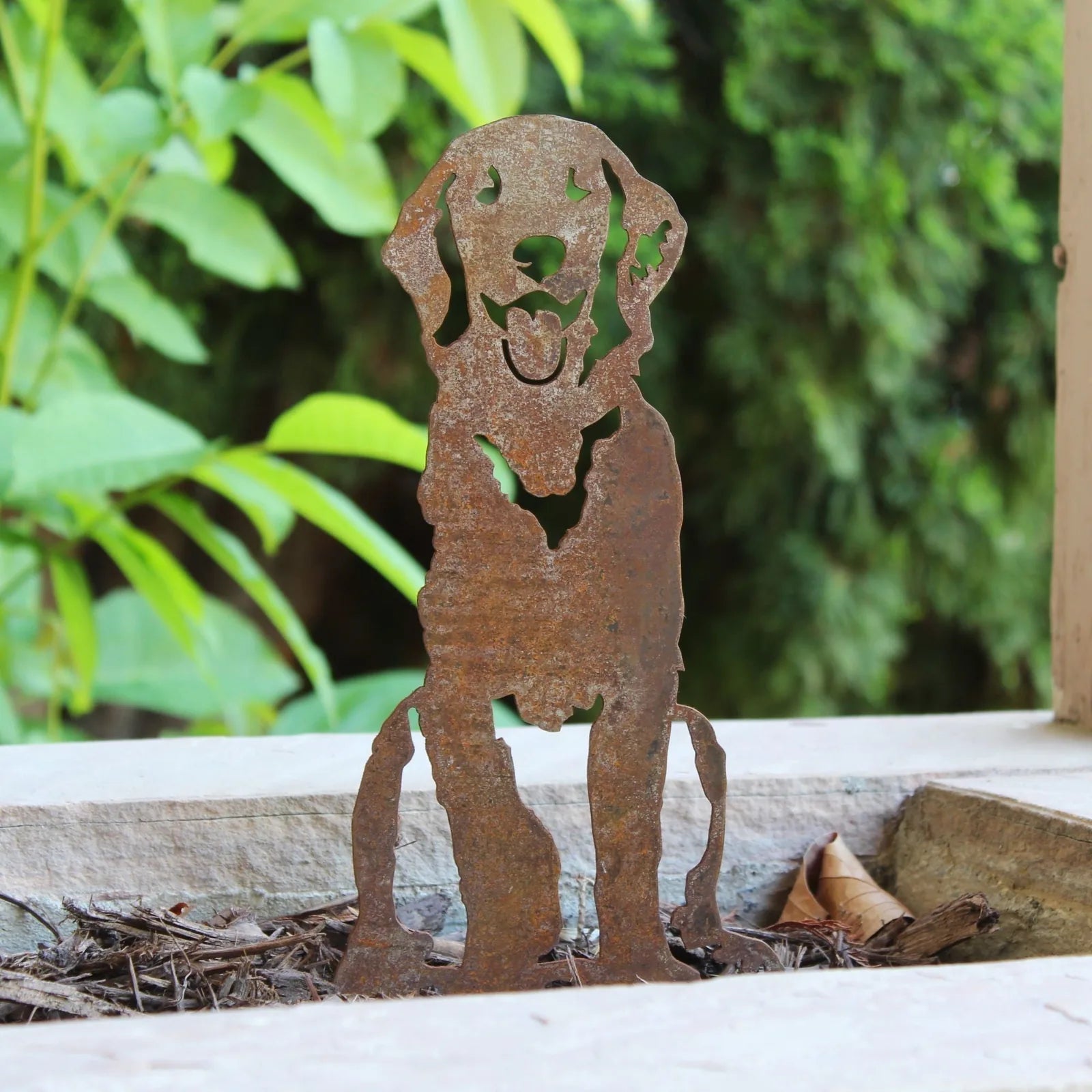 Handcrafted Corten steel silhouette of a Flat-Coated Retriever, displaying natural rust patina, set against greenery.