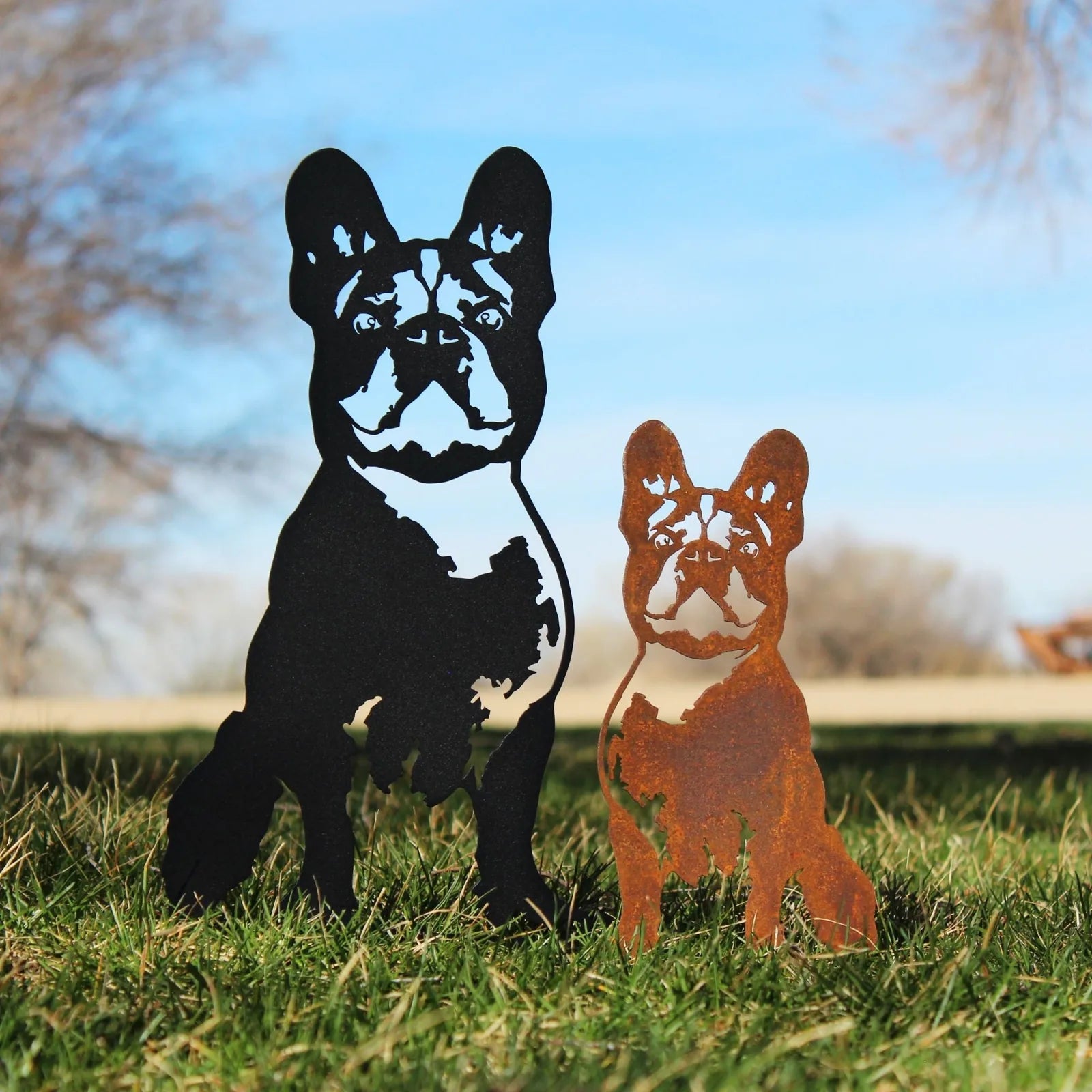 Handmade French Bulldog metal art in black and Corten steel, showcasing intricate details, set against green grass.