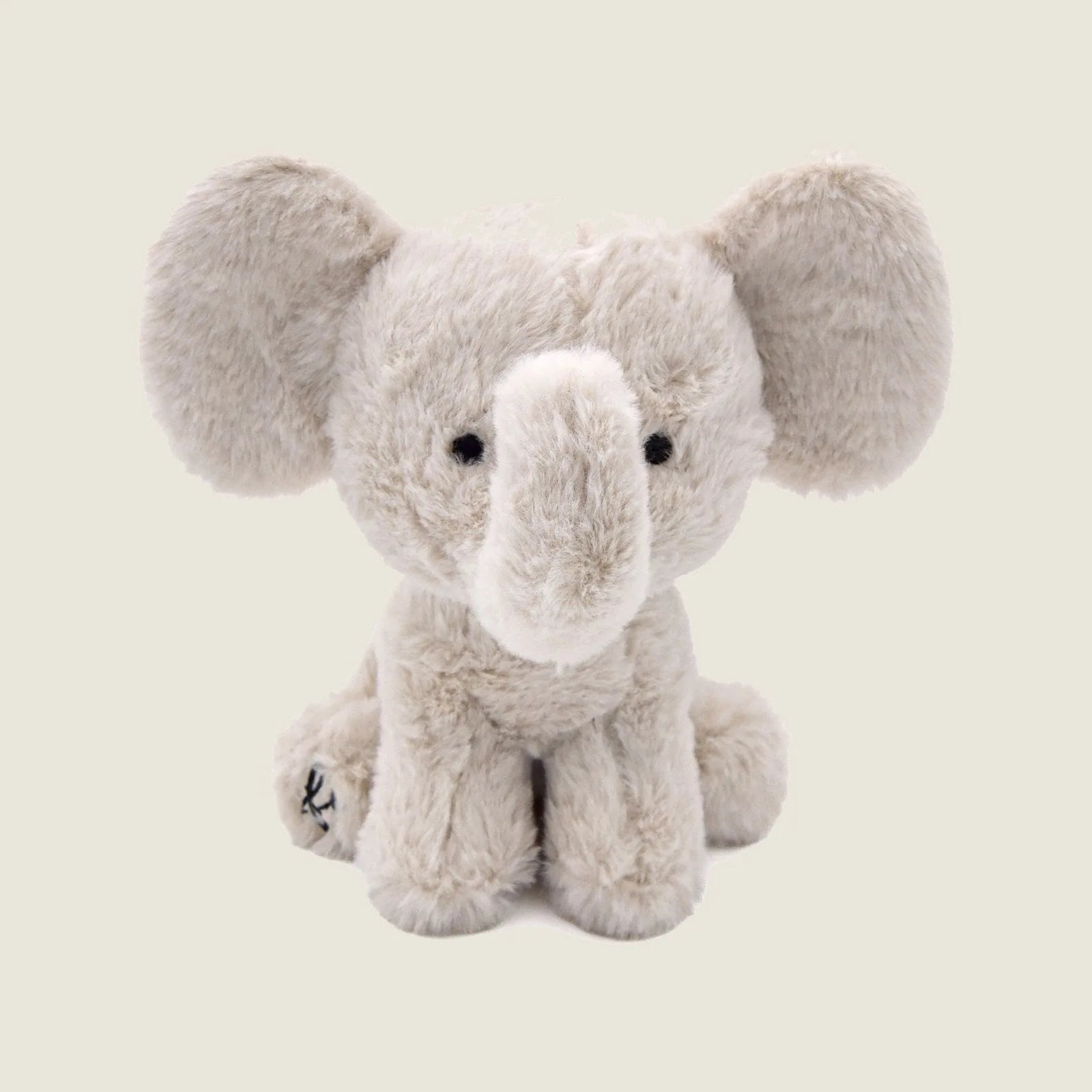 Soft beige plush elephant toy with large ears, embroidered eyes, and a cute smile, perfect for gentle chewers and snugglers.