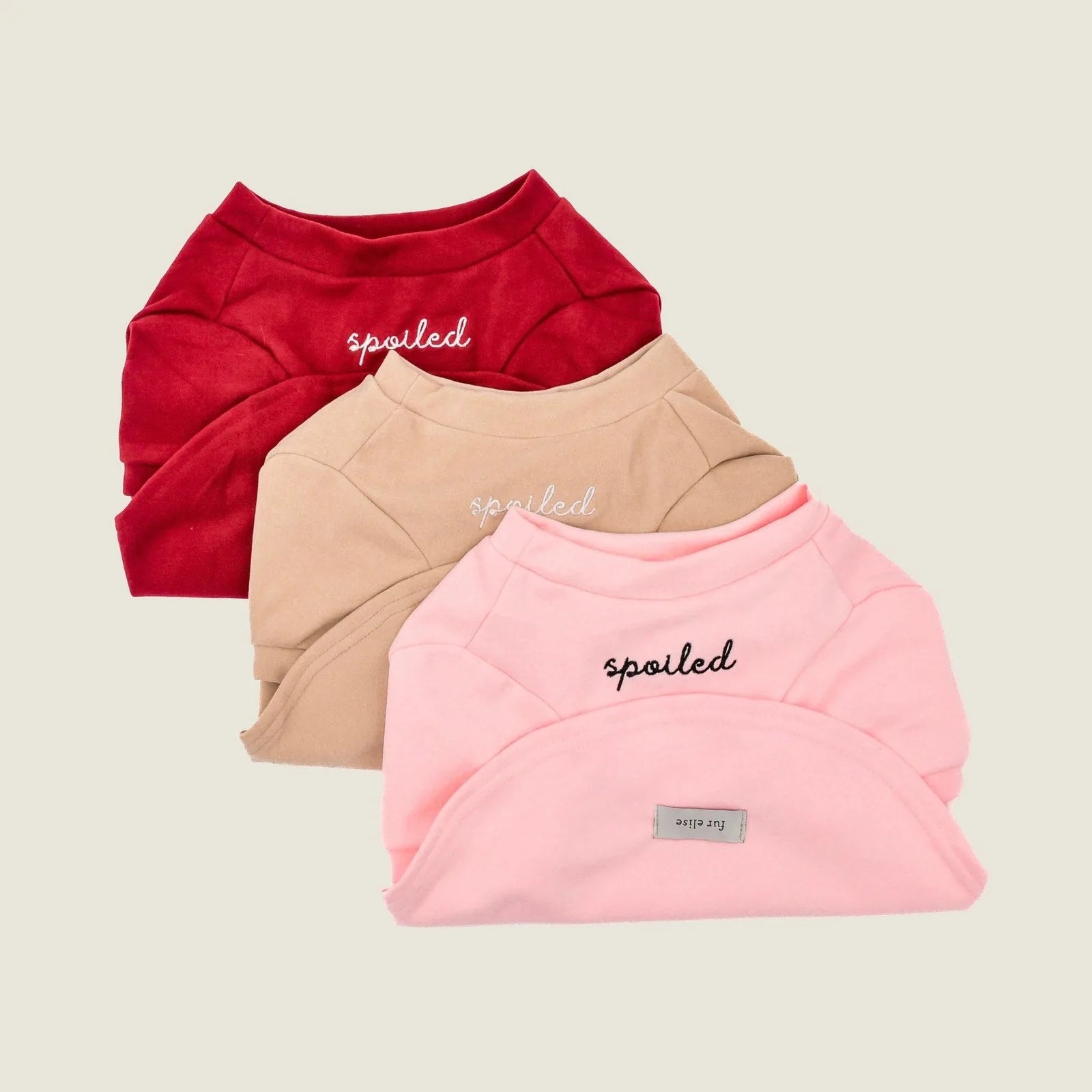 Soft fleece dog shirts in red, tan, and pink with "spoiled" embroidery, perfect for stylish pet comfort.