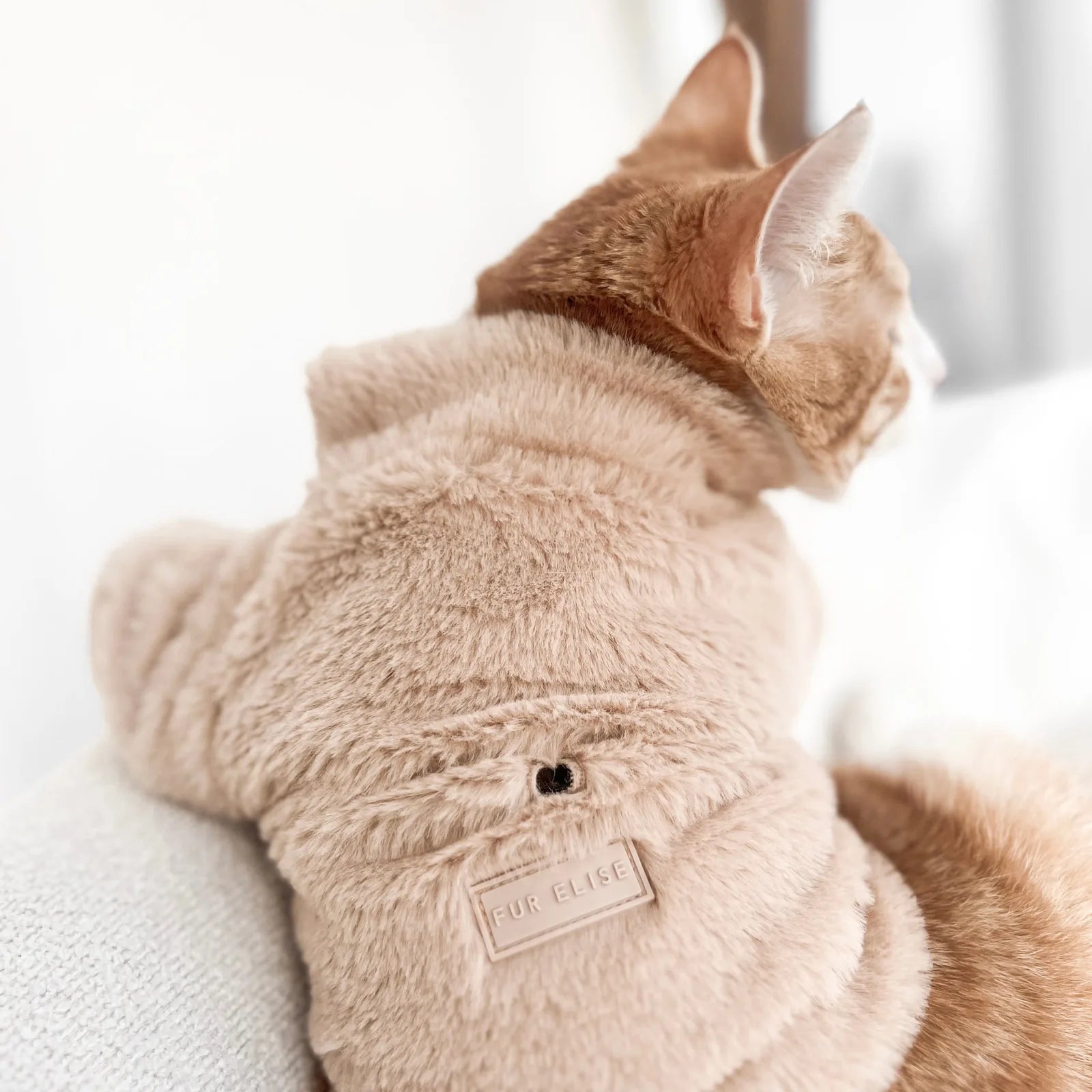 Cozy sand-colored faux fur pet coat with a rubber Fur Elise logo and a leash hole, perfect for small to medium dogs.