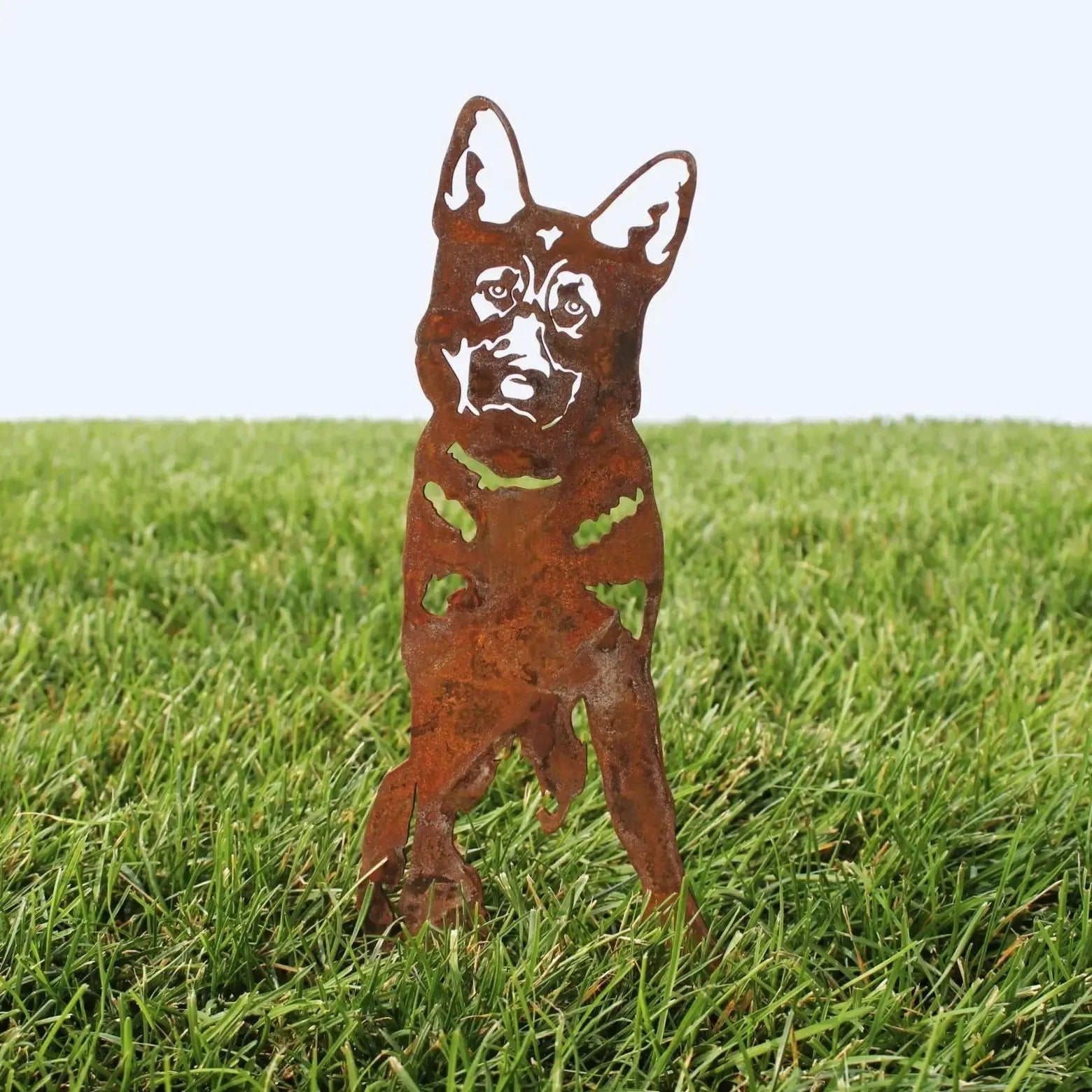Rusty Corten steel German Shepherd silhouette standing in grass, showcasing intricate details and sturdy design.