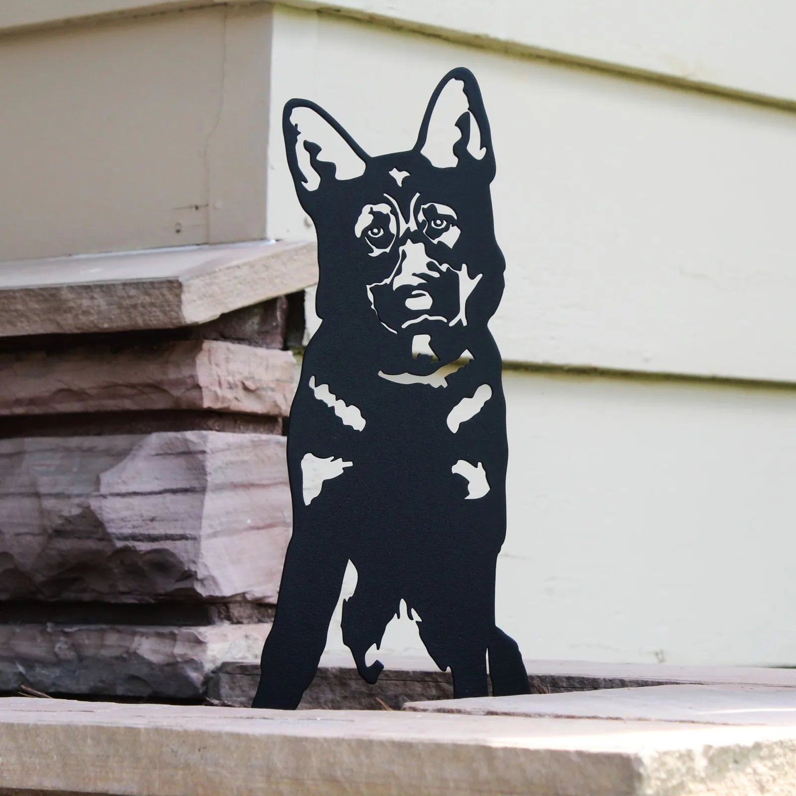 Black silhouette of a German Shepherd dog against a light-colored wall, showcasing detailed craftsmanship in metal art.