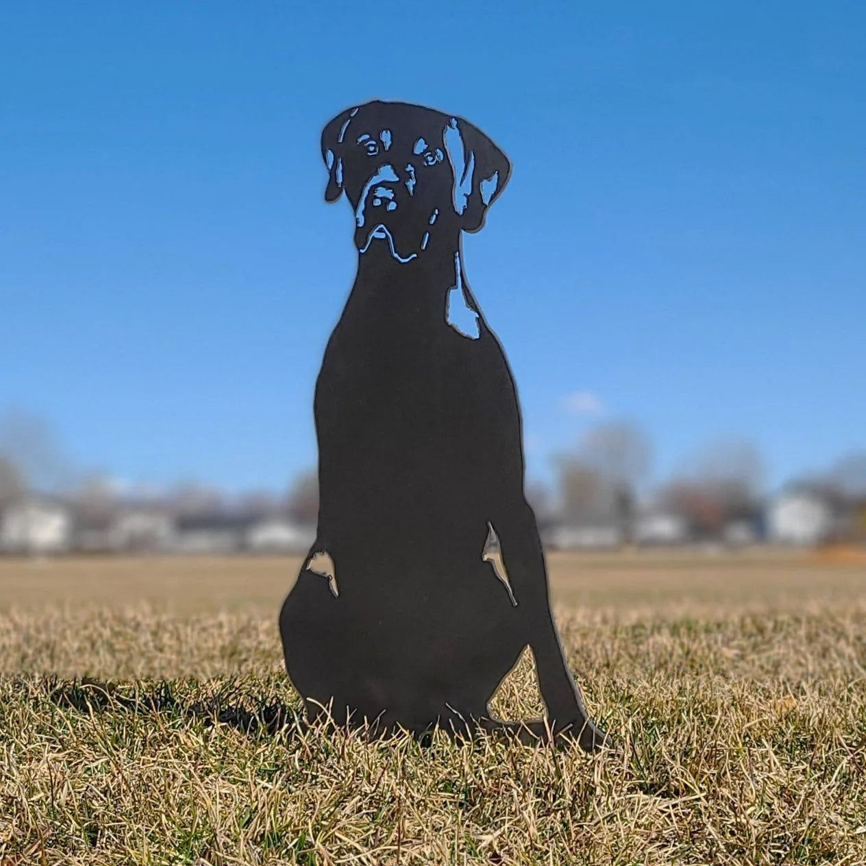 German Shorthaired Pointer silhouette in matte black metal, set against a clear blue sky and grassy field.