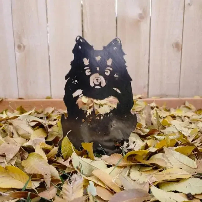German Spitz silhouette metal wall art in a matte black finish, surrounded by colorful autumn leaves.