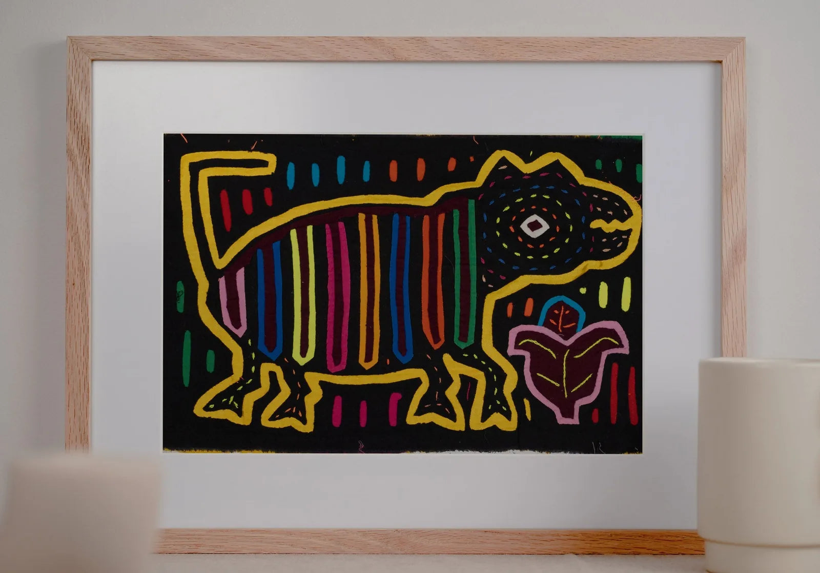 Colorful hand-stitched Mola featuring a playful dog with striped patterns, framed against a dark background.