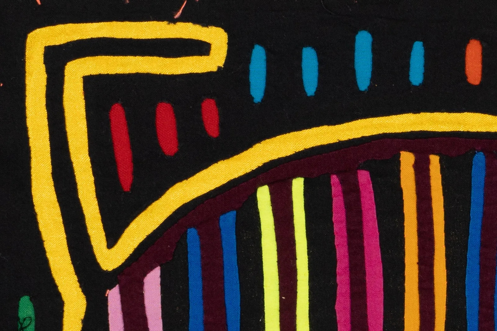 Colorful hand-stitched Mola featuring bold geometric patterns in yellow, red, blue, and pink on a black background.