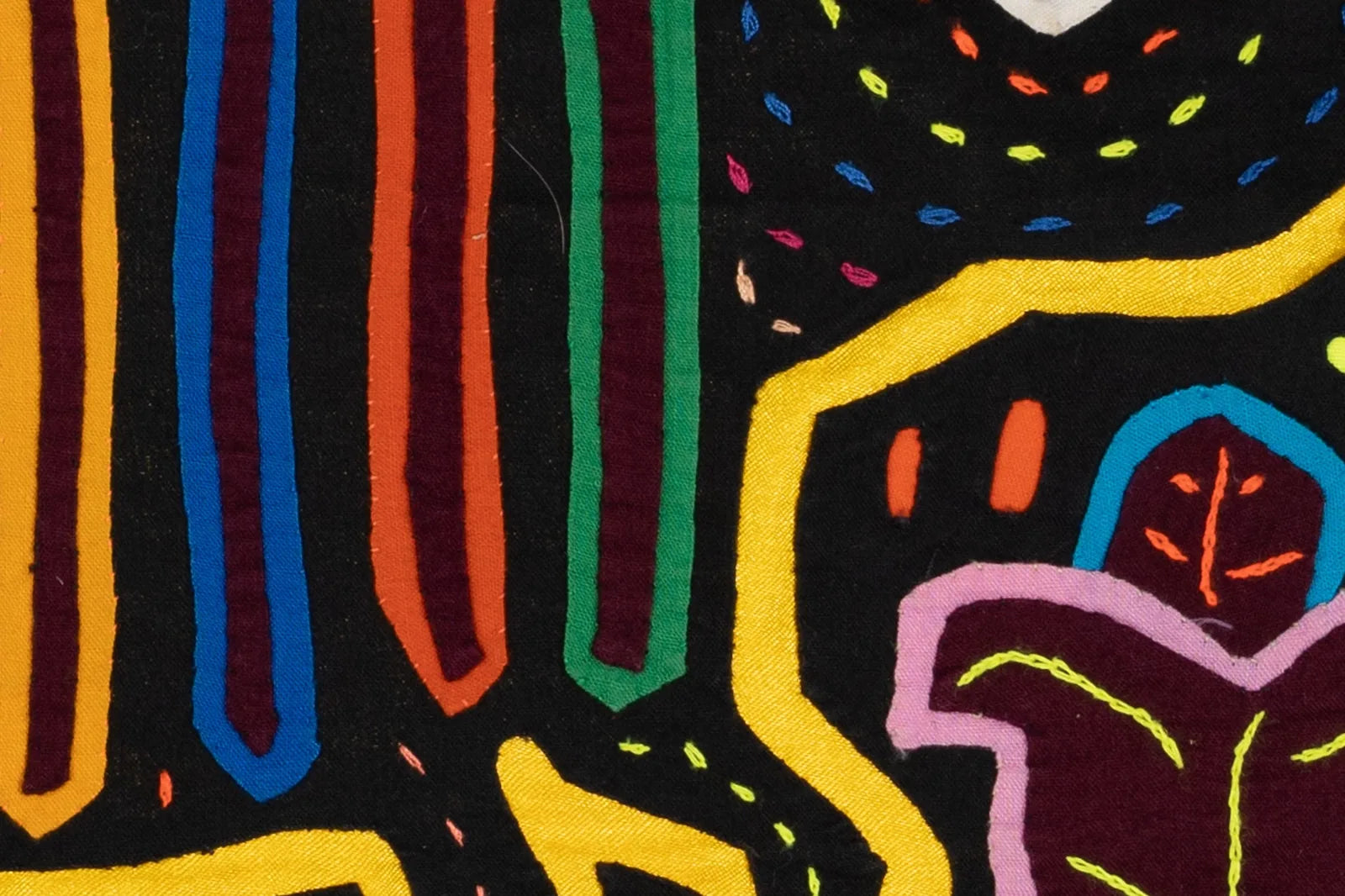 Colorful geometric patterns in vibrant threads on a black background, showcasing hand-stitched Panama Mola textile art.