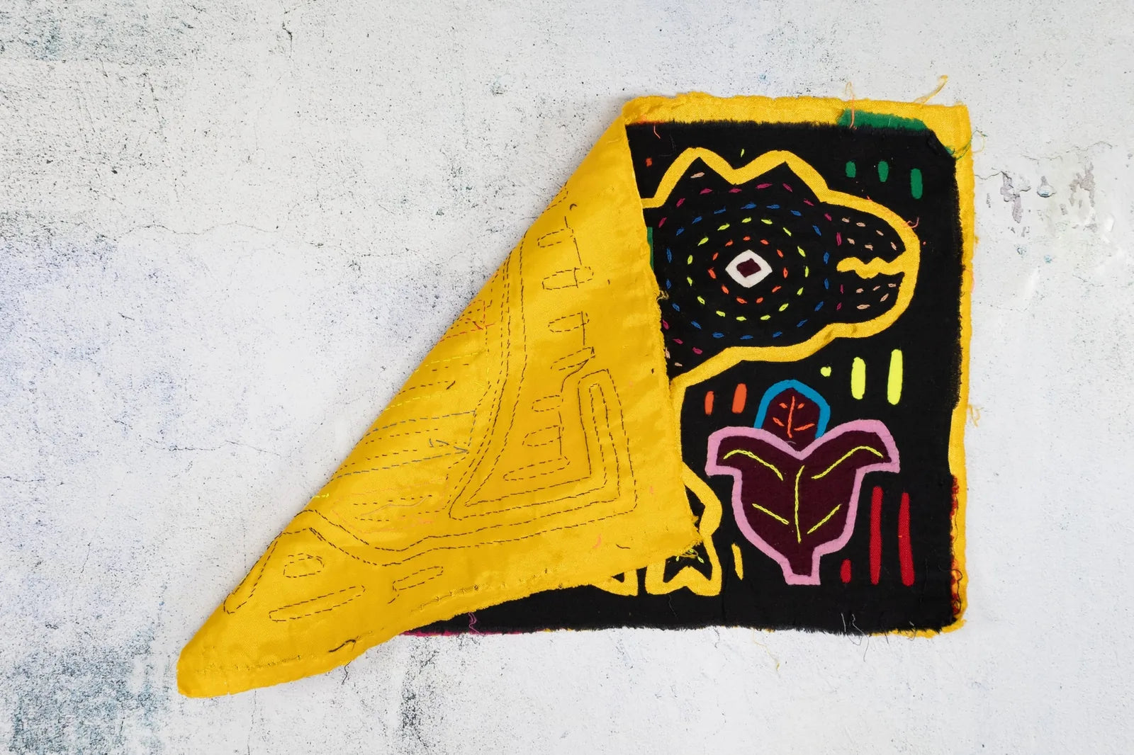 Bright yellow and black hand-stitched Mola featuring a playful geometric design with foliage motifs.