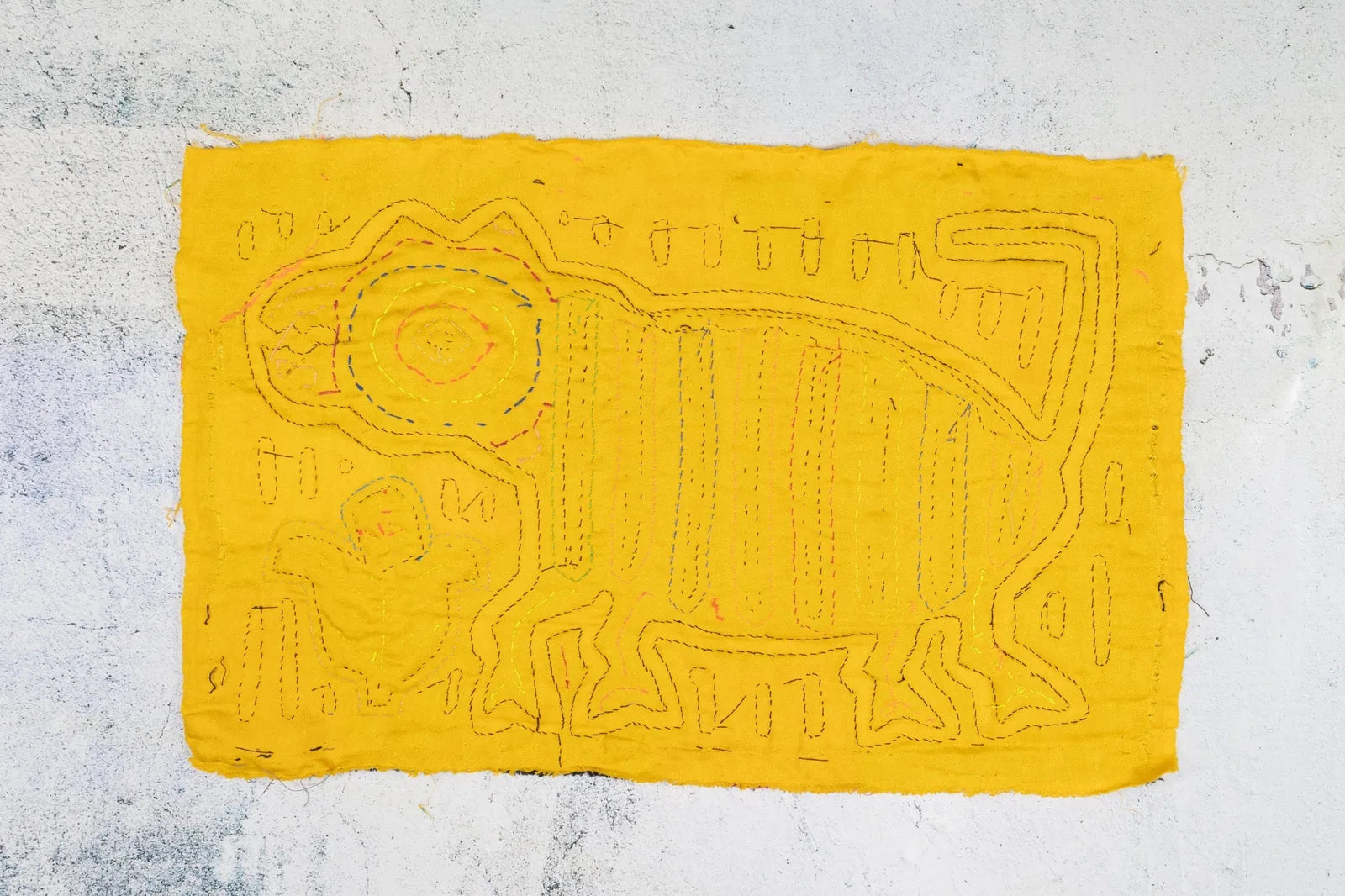 Hand-stitched yellow fabric Mola featuring a playful dog design, embodying traditional Panama textile art.