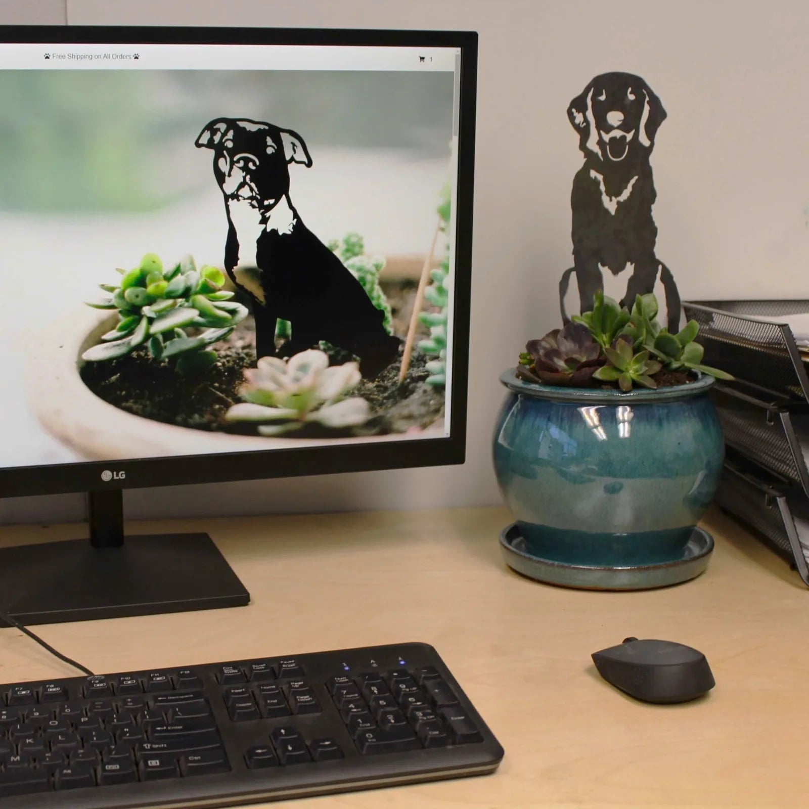 Handcrafted black metal silhouette of a dog sitting among succulent plants on a desk next to a computer monitor.