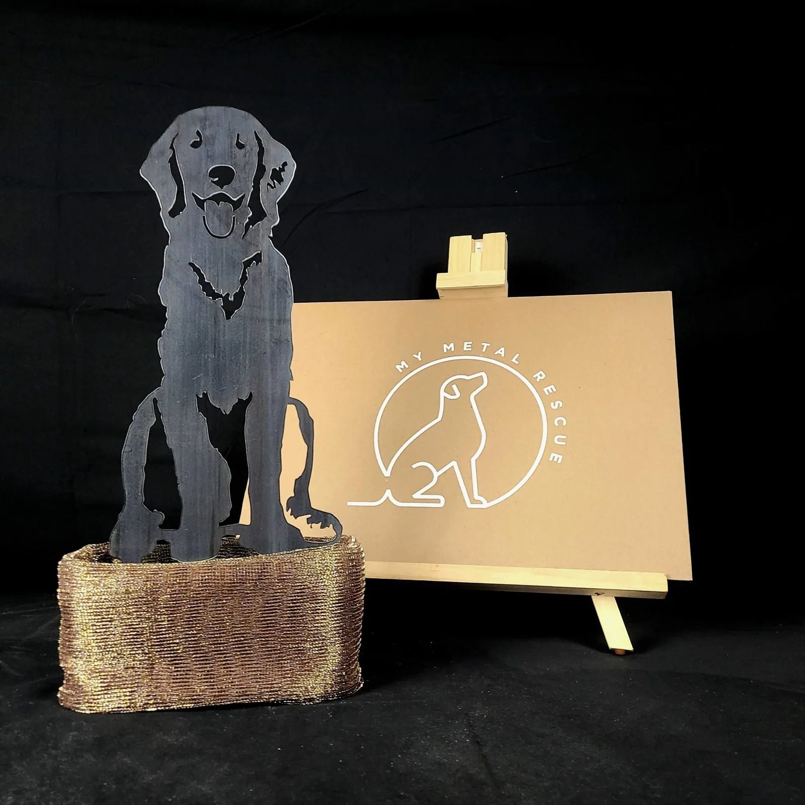 Handcrafted black metal silhouette of a Golden Retriever sitting, displayed on a textured golden base, ideal for home décor.