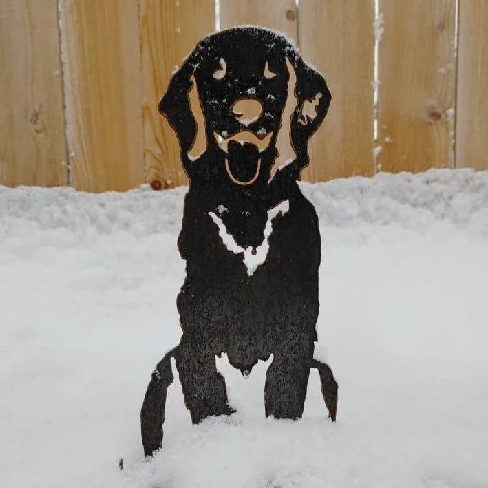 Handcrafted black metal silhouette of a sitting Golden Retriever, displayed in snow, showcasing its calm demeanor.