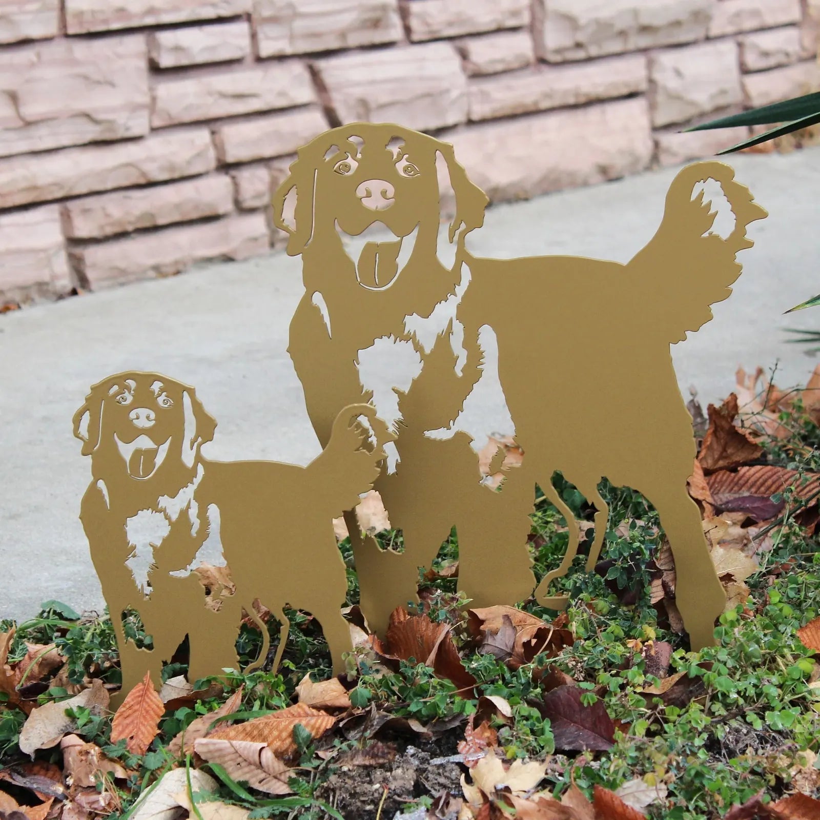Golden Retriever metal silhouette in gold, showcasing two playful dogs among fallen leaves in a garden setting.