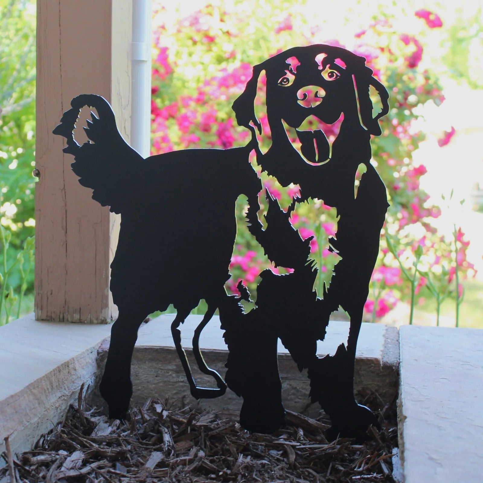 Black metal silhouette of a standing Golden Retriever, showcasing detailed features against a vibrant floral background.