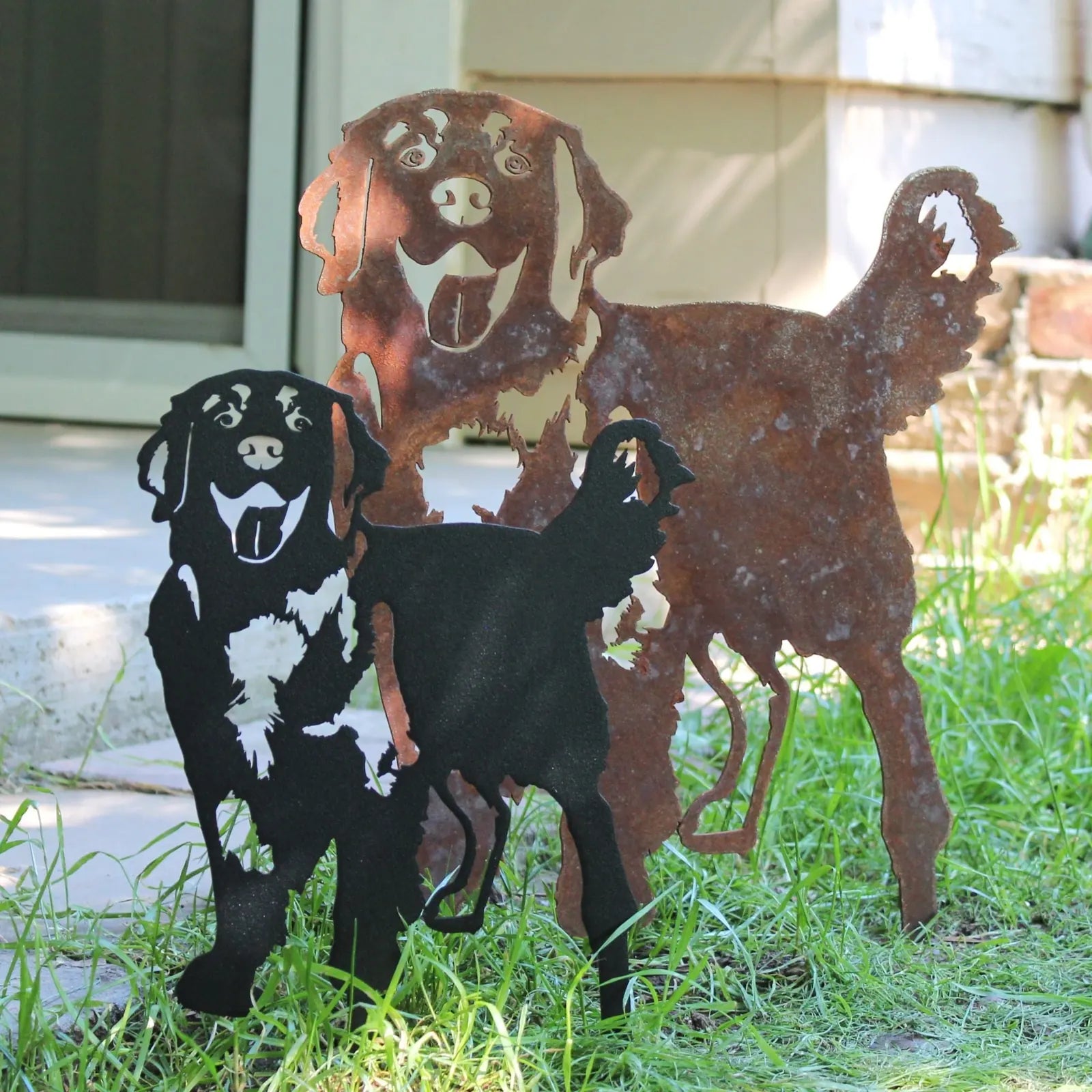 Golden Retriever silhouettes in Corten steel and black finish, showcasing playful poses in grass and stone setting.