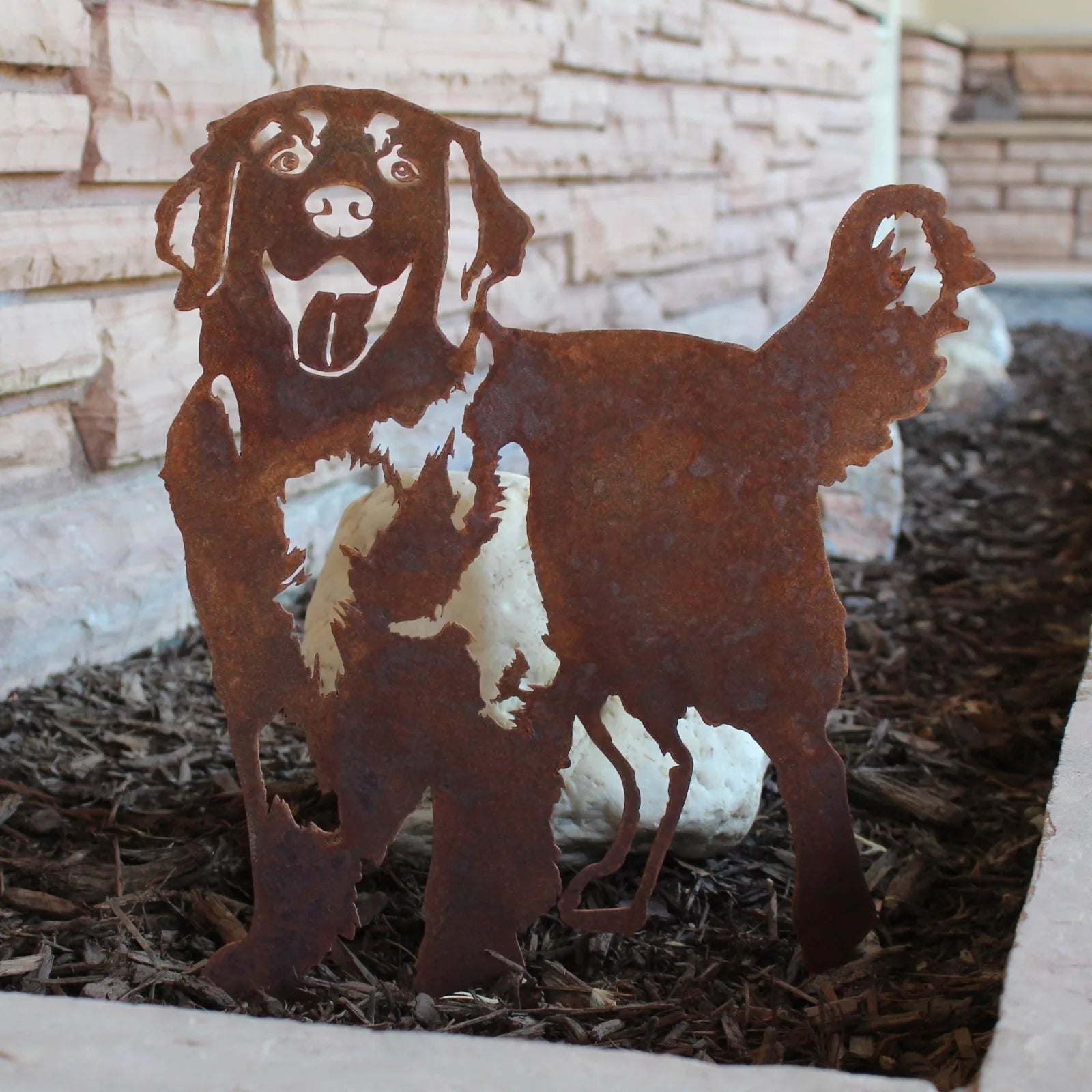 Rusty metal silhouette of a Golden Retriever standing, with a playful expression, in a garden setting.