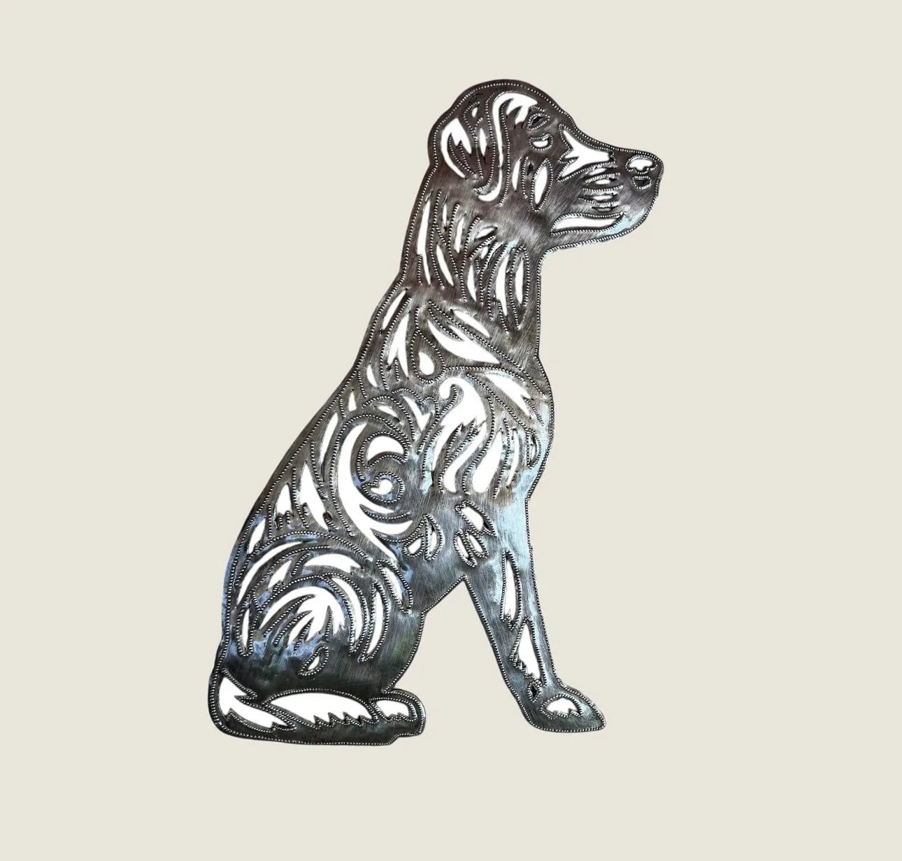 Handcrafted metal art of a sitting dog with intricate swirl patterns, showcasing a rustic finish from recycled materials.