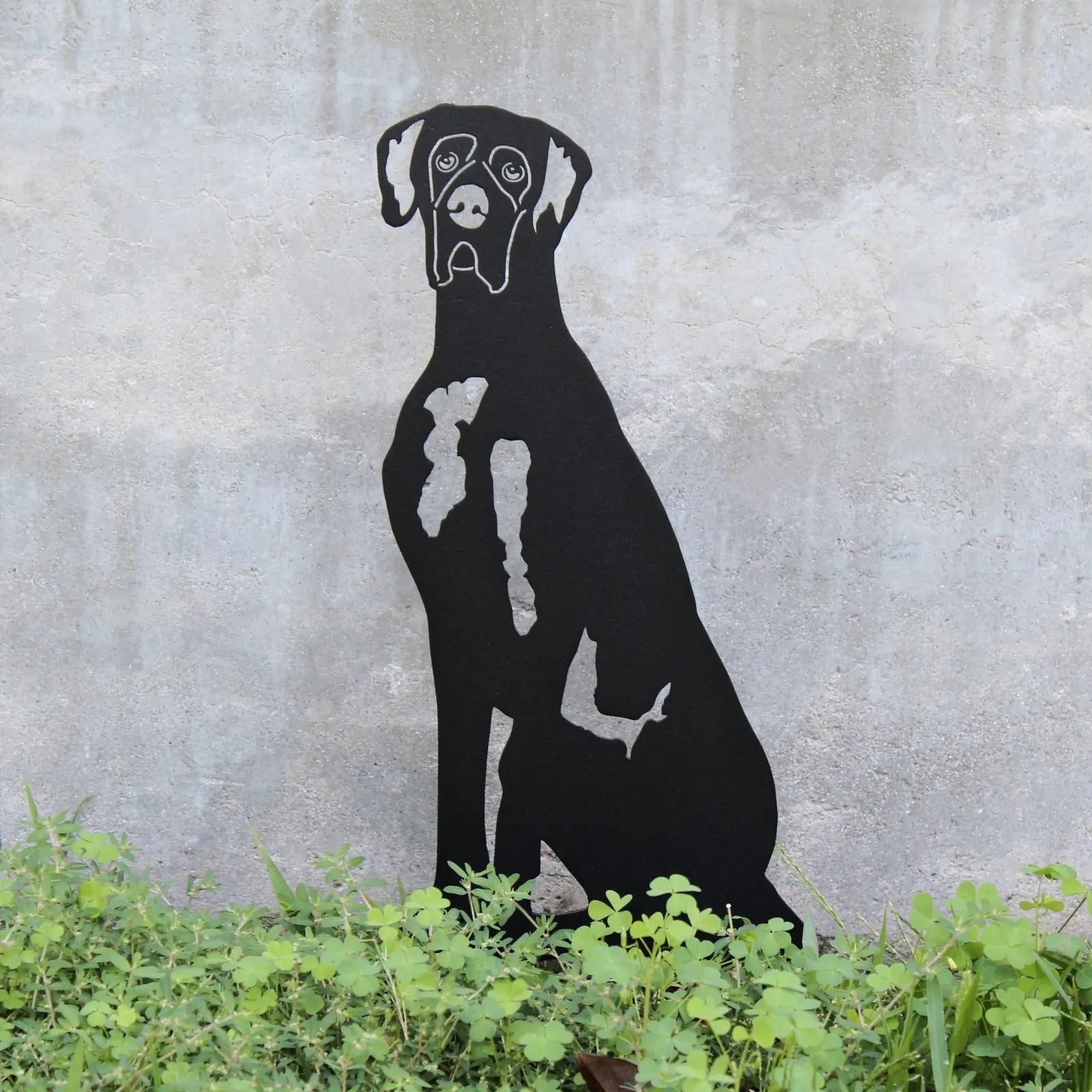 Great Dane silhouette in matte black metal, showcasing elegant lines, surrounded by vibrant greenery.