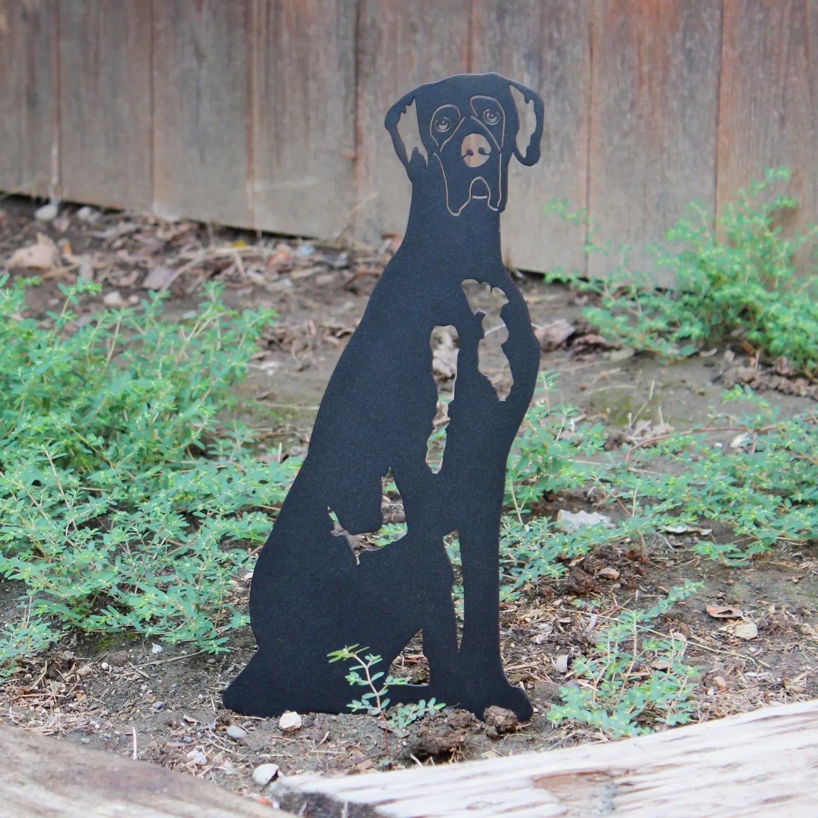 Black Great Dane silhouette garden art made from weathering steel, featuring intricate detailing and surrounded by greenery.