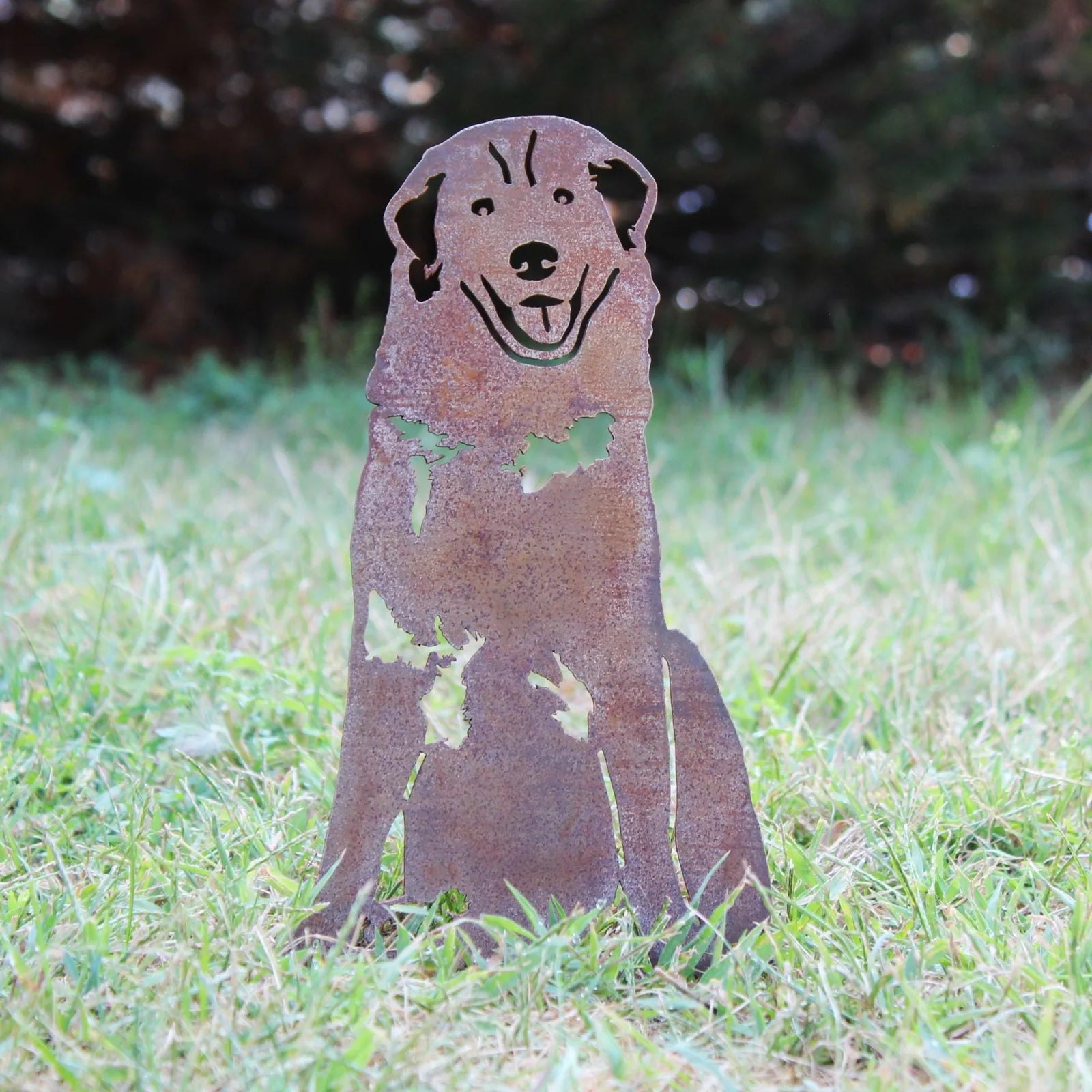 Great Pyrenees metal silhouette in weathered Corten steel, sitting on grass, showcasing intricate cut-out details.