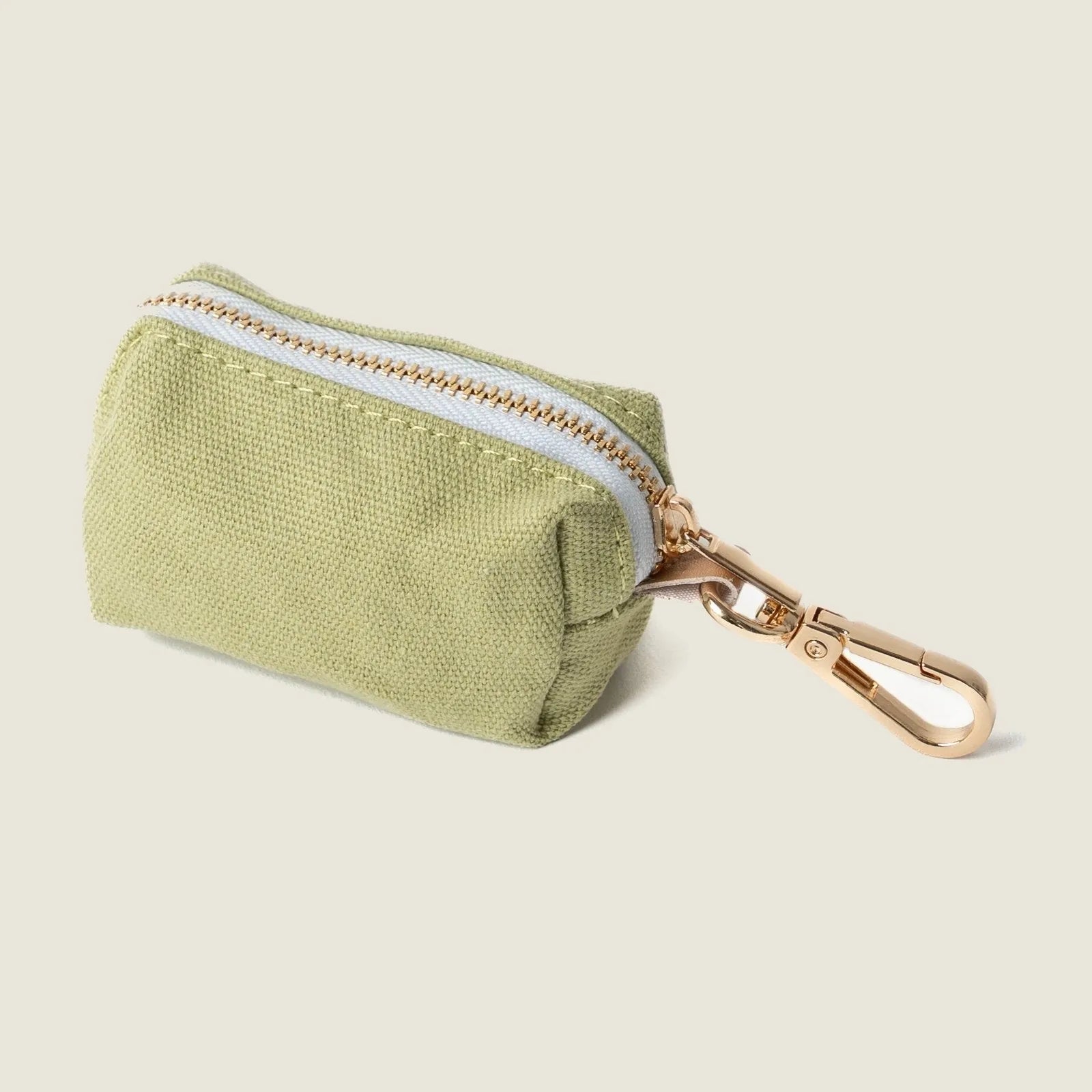 Green poop bag holder with a gold clip and white zipper, designed for easy access during dog walks.