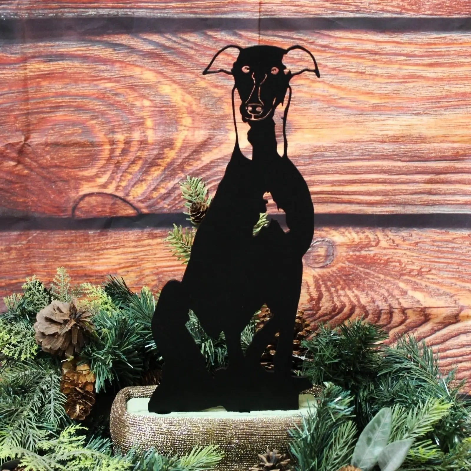 Black metal silhouette of a Greyhound dog among greenery, showcasing a durable outdoor decor feature.