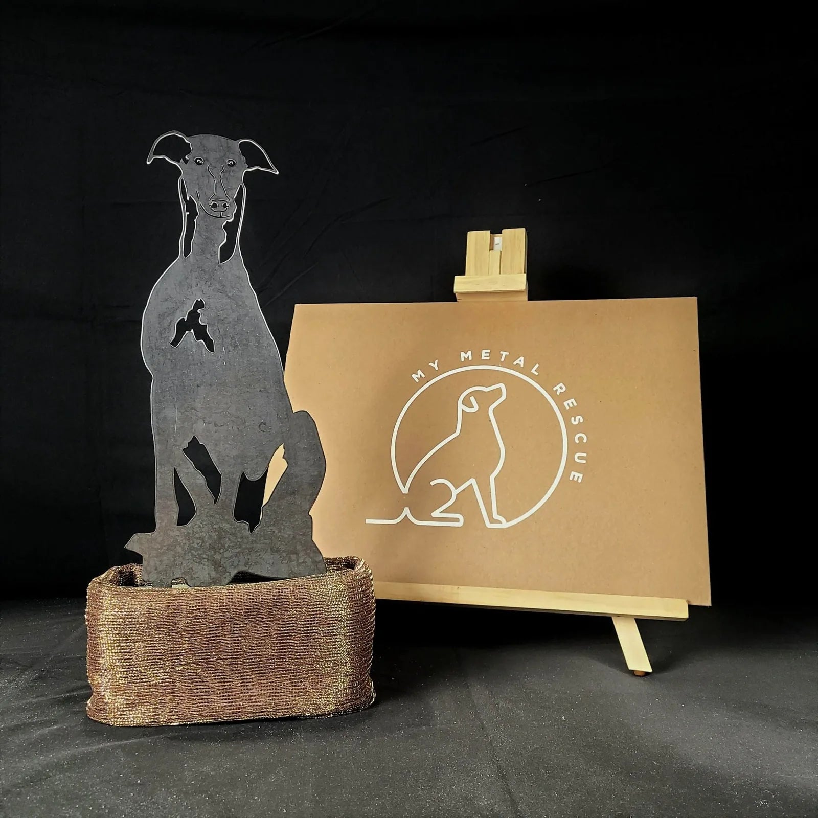 Handcrafted greyhound metal silhouette in Corten steel, displayed in a textured brown base with a My Metal Rescue sign.