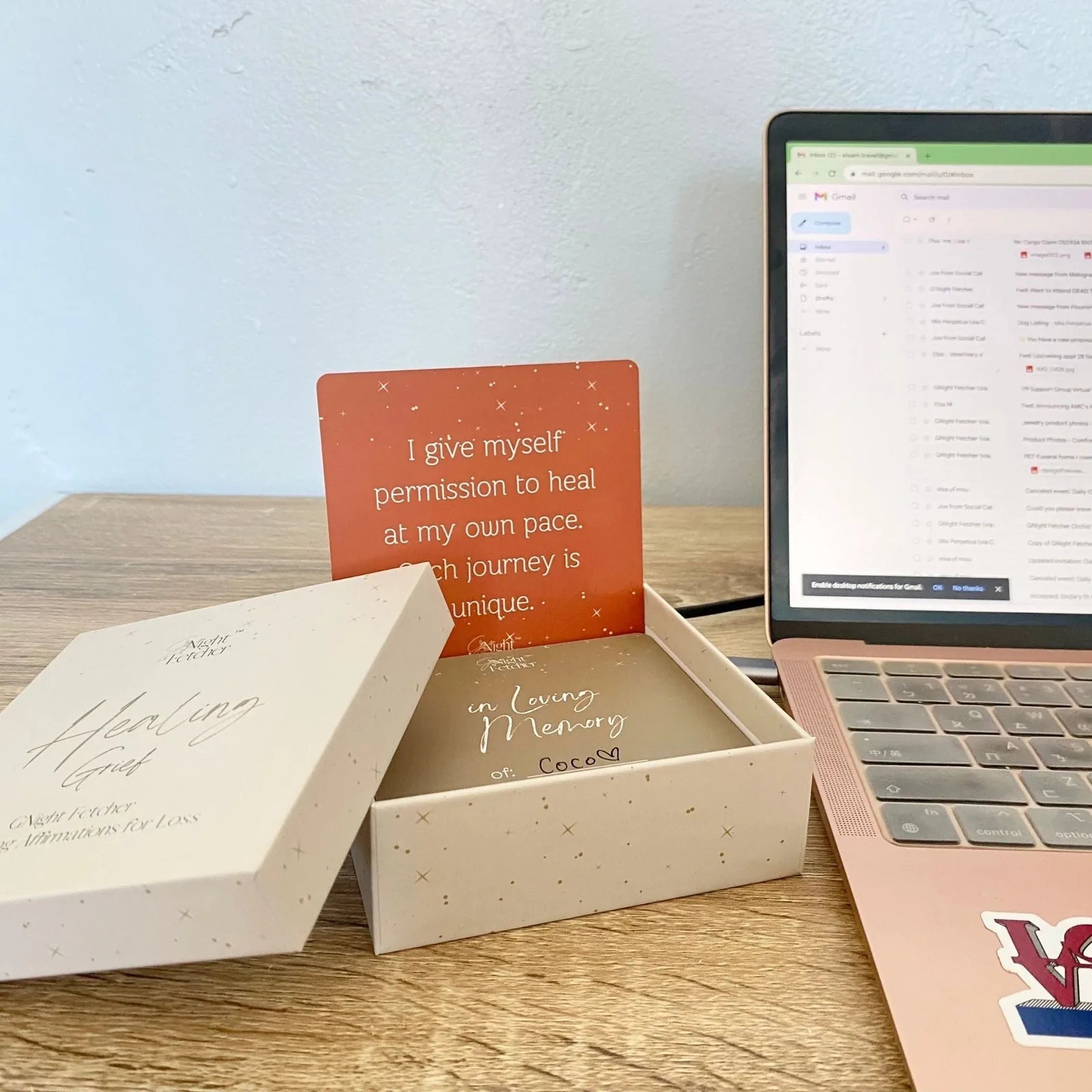 Inside a cream box, a grief affirmation card reads "I give myself permission to heal" against an orange background.