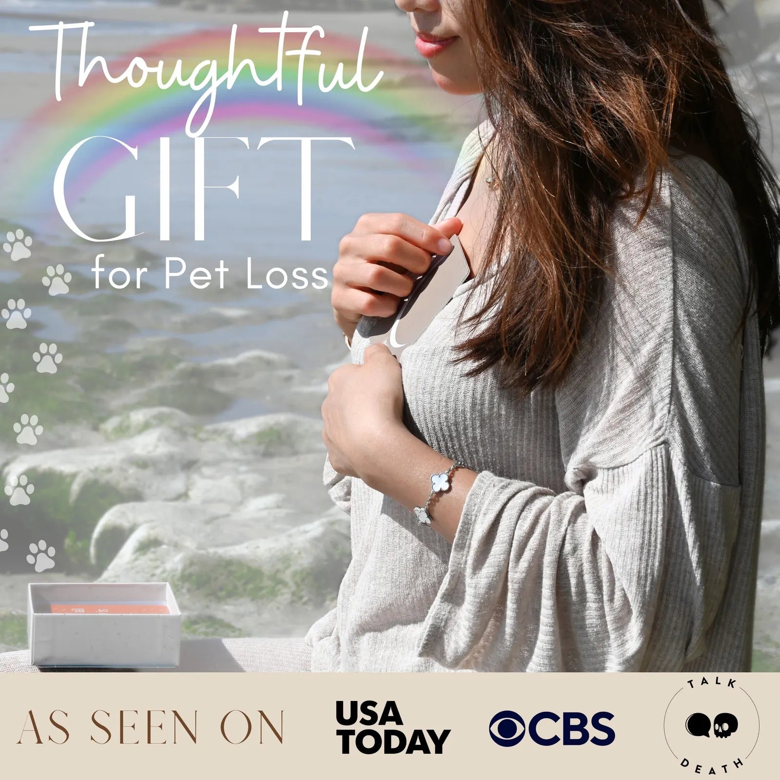A woman in a light gray top holds a card, showcasing Grief Affirmation Cards for pet loss, with a rainbow in the background.