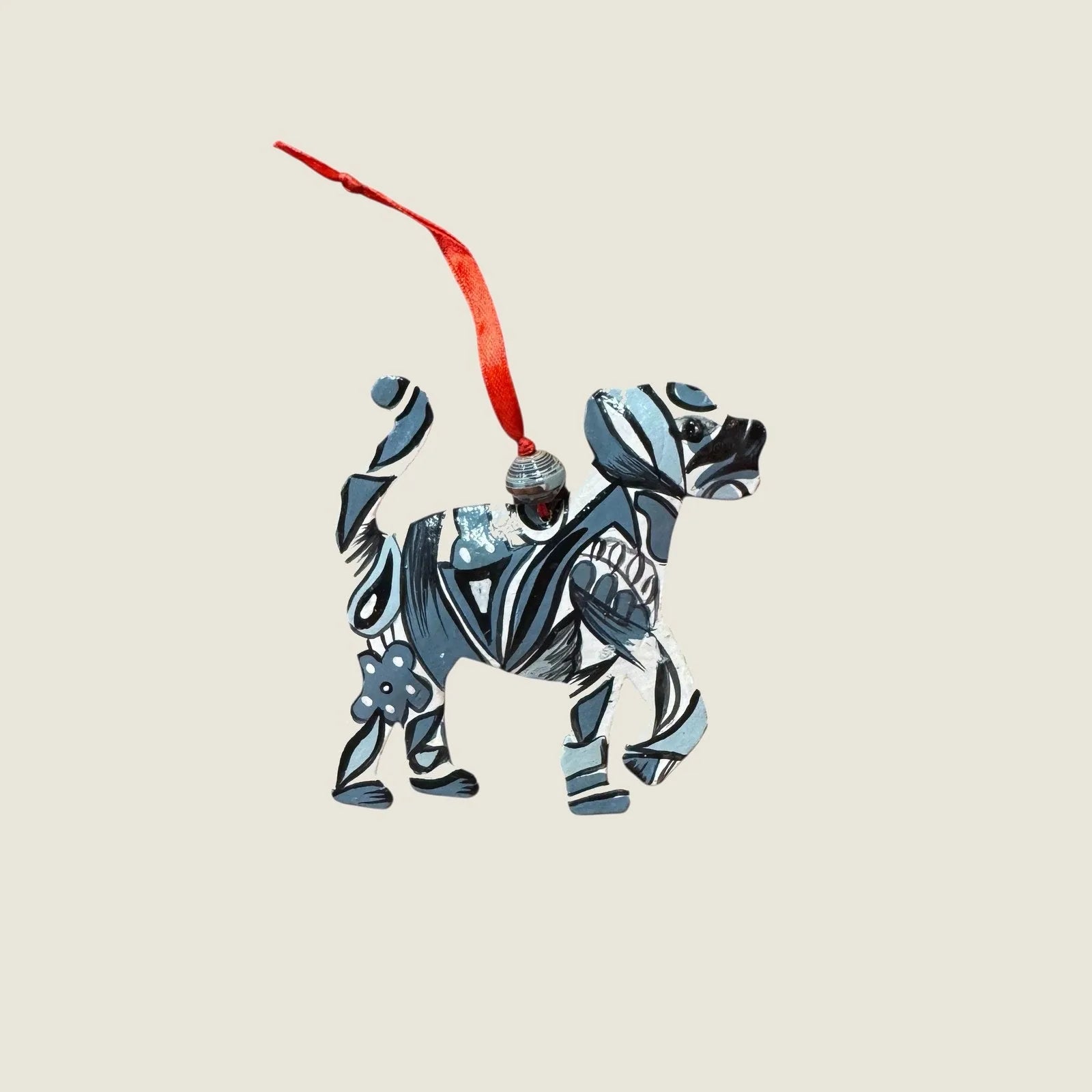 Hand-painted blue and black steel drum dog ornament with a red hanging ribbon, showcasing unique patterns.