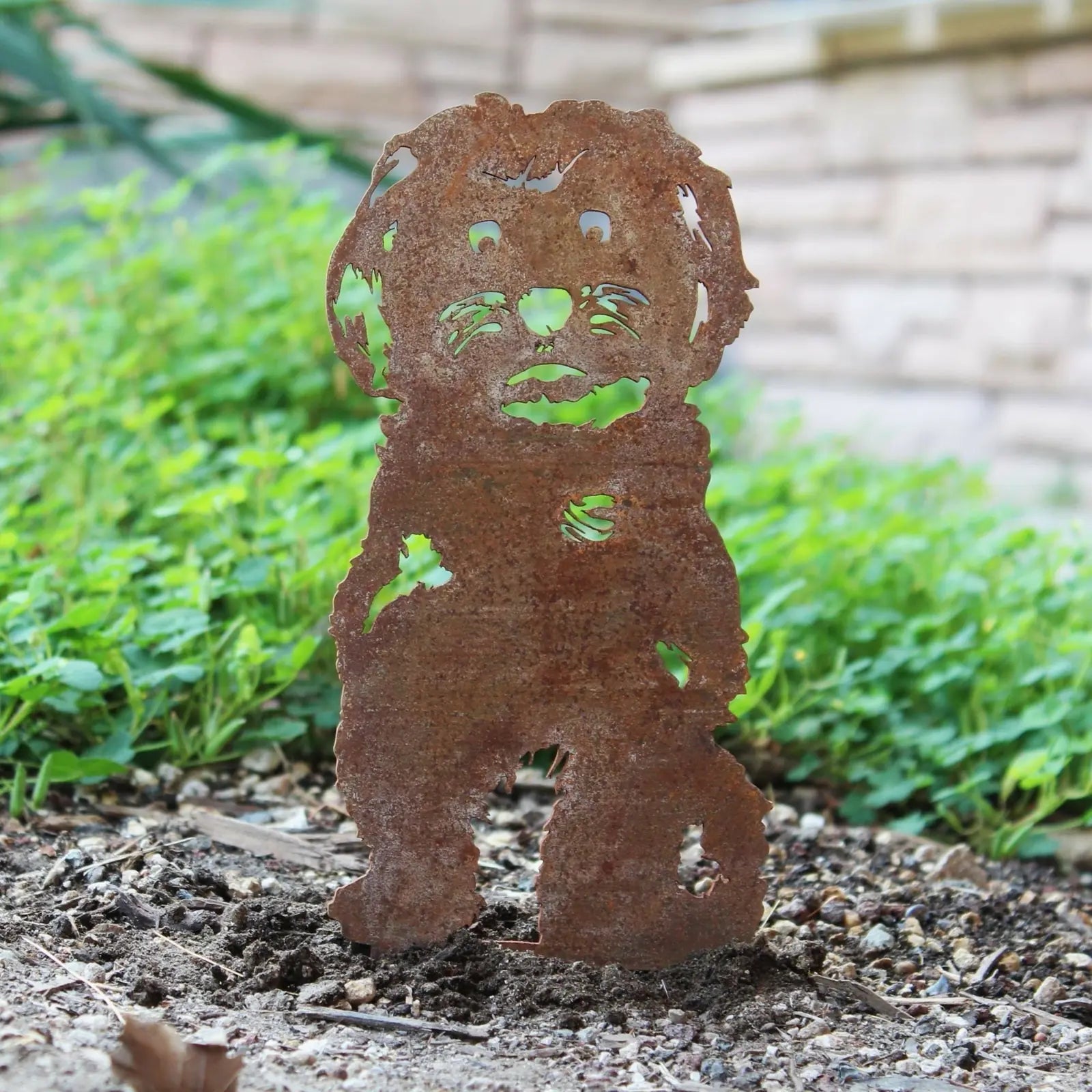 Rusty Havanese silhouette made of Corten steel, displayed among greenery in a garden setting.