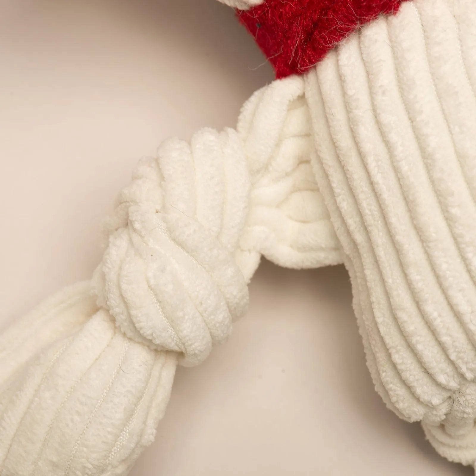 Soft, white plush dog toy with knotted limbs and a red accent, designed for playful tugging and chewing.