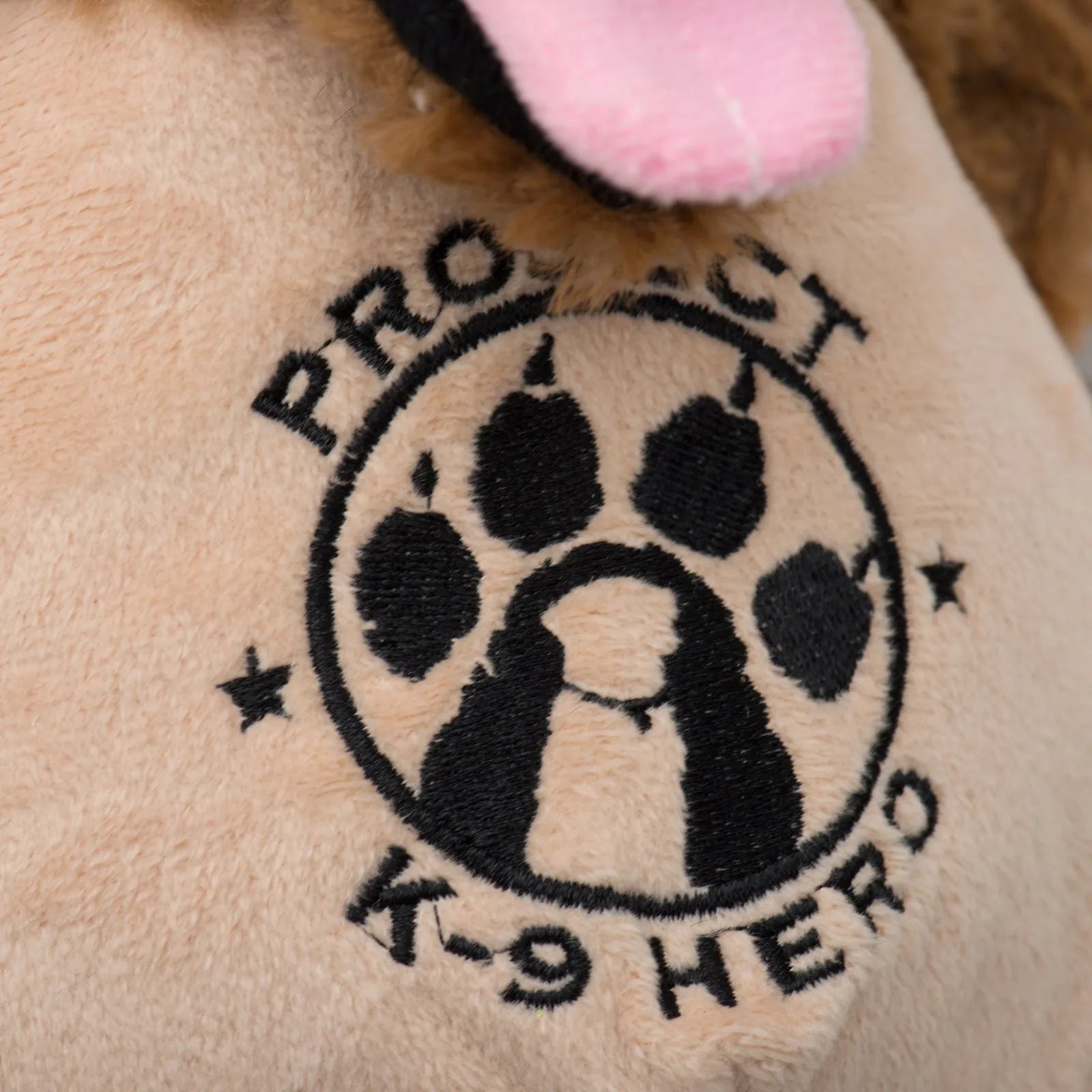 Embroidered "Project K-9 Hero" logo featuring a paw print on soft beige plush fabric.