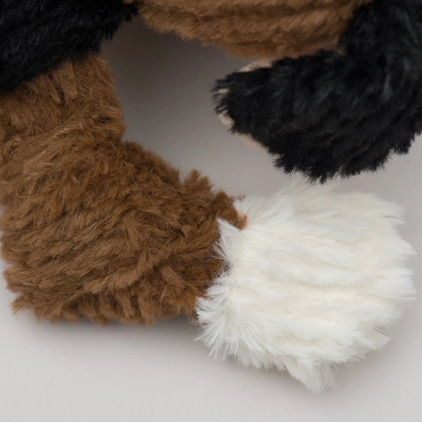 Soft plush toy limb in brown and black with a fluffy white paw, designed for interactive play and durability.